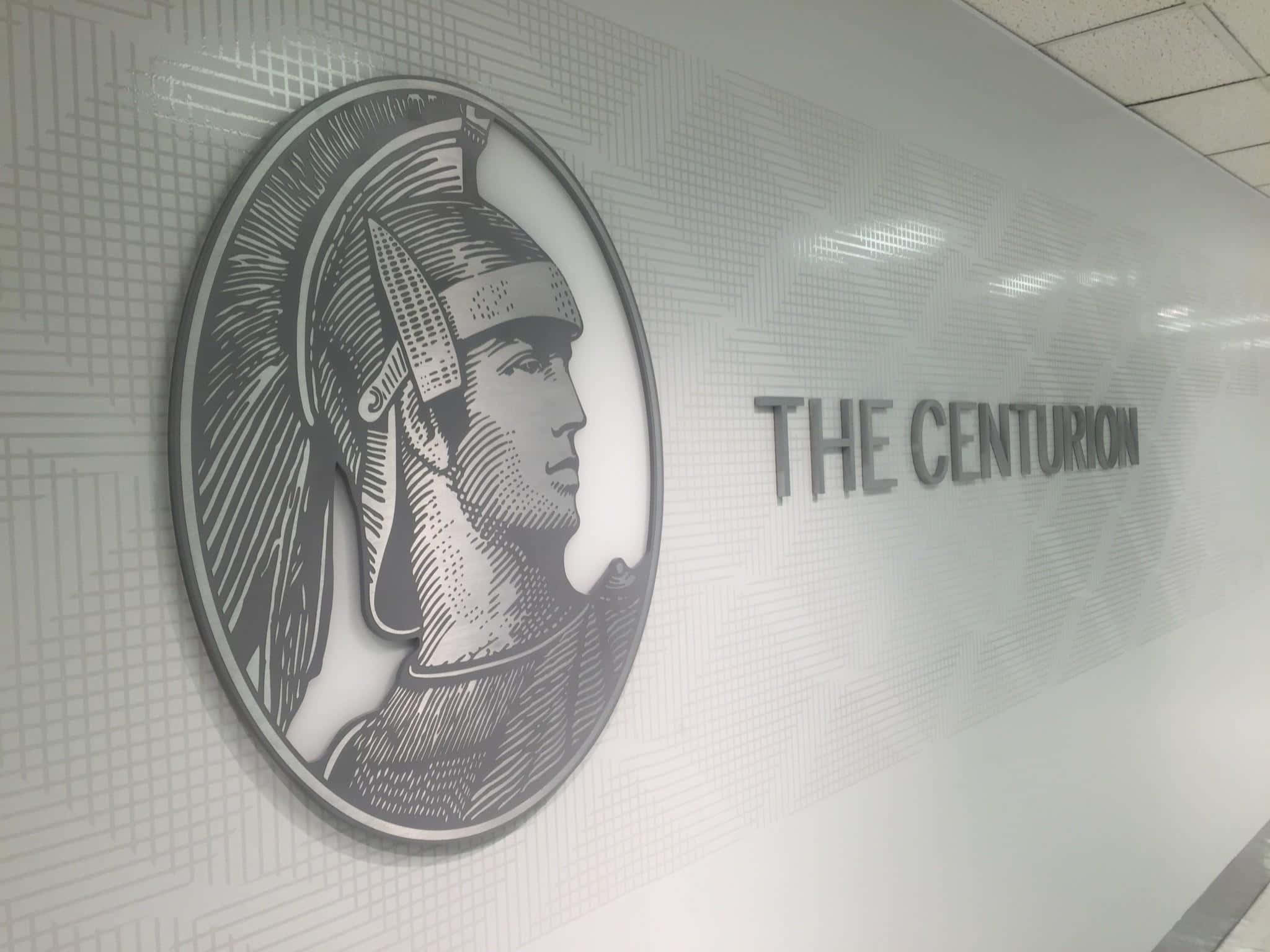 美國運通 桌布 壁紙 — 一面時尚現代牆壁，在THE CENTURION文字旁邊有一個羅馬百夫長側面的單色壓花標誌。