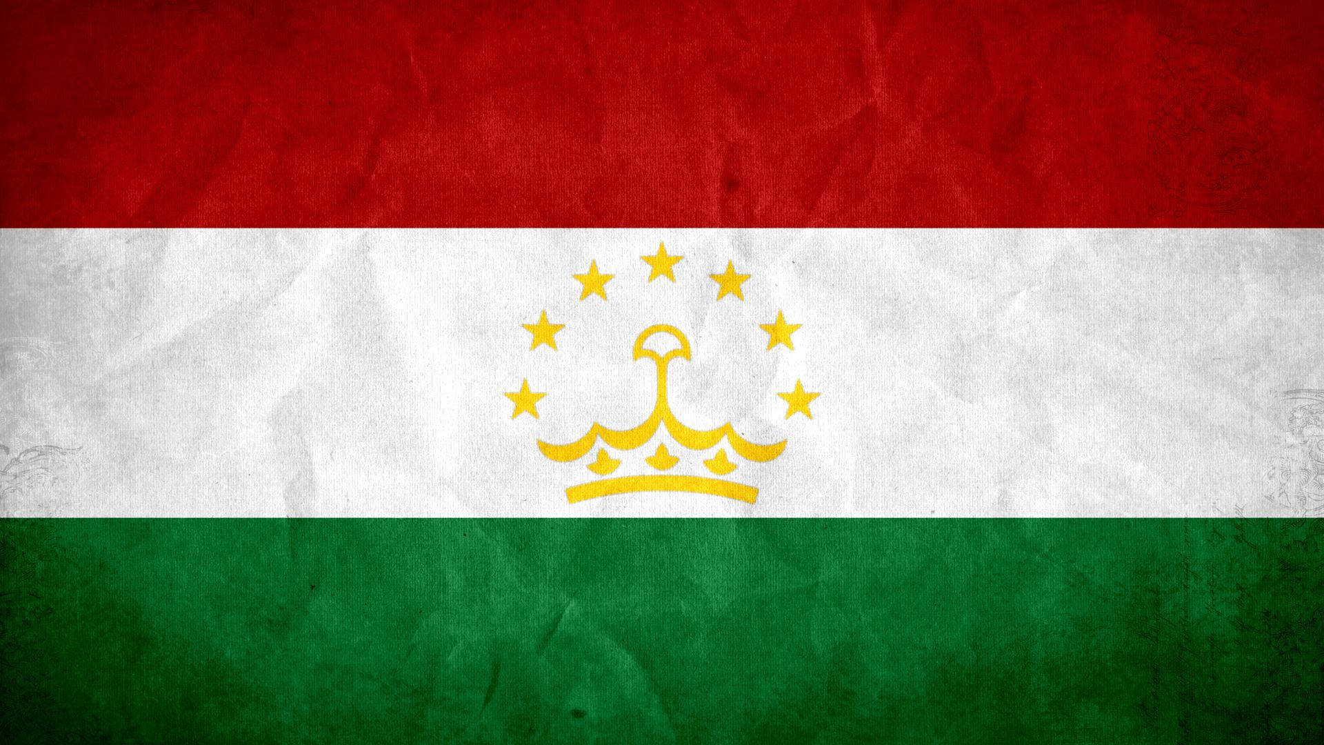 Tajikistan 桌布 壁紙 — 一面有紋理、皺巴巴的塔吉克斯坦國旗，帶有紅、白、綠橫條紋，中央有金色皇冠，周圍環繞星星。