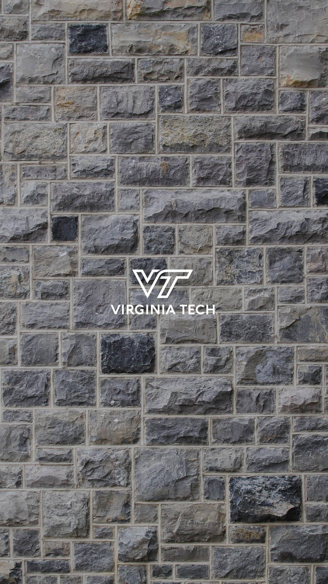 Virginia Tech 桌布 壁紙 — 一面有紋理的灰色石牆，中央有一個白色的維吉尼亞理工大學標誌。