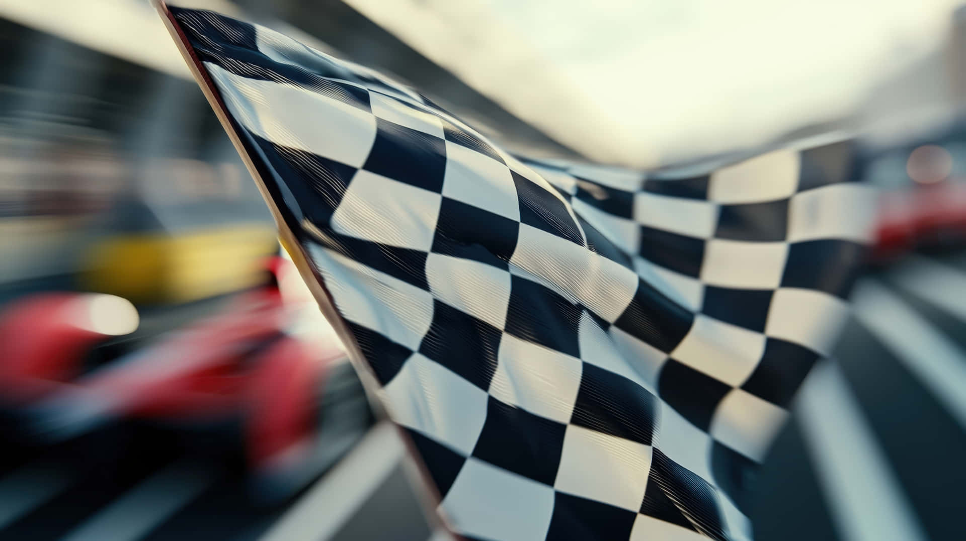 Checkered Racing Flag Waving at High-Speed Finish Line 壁紙 — 一面格子旗在前景中動態飄揚，而一輛模糊的賽車在賽道上疾馳而過。