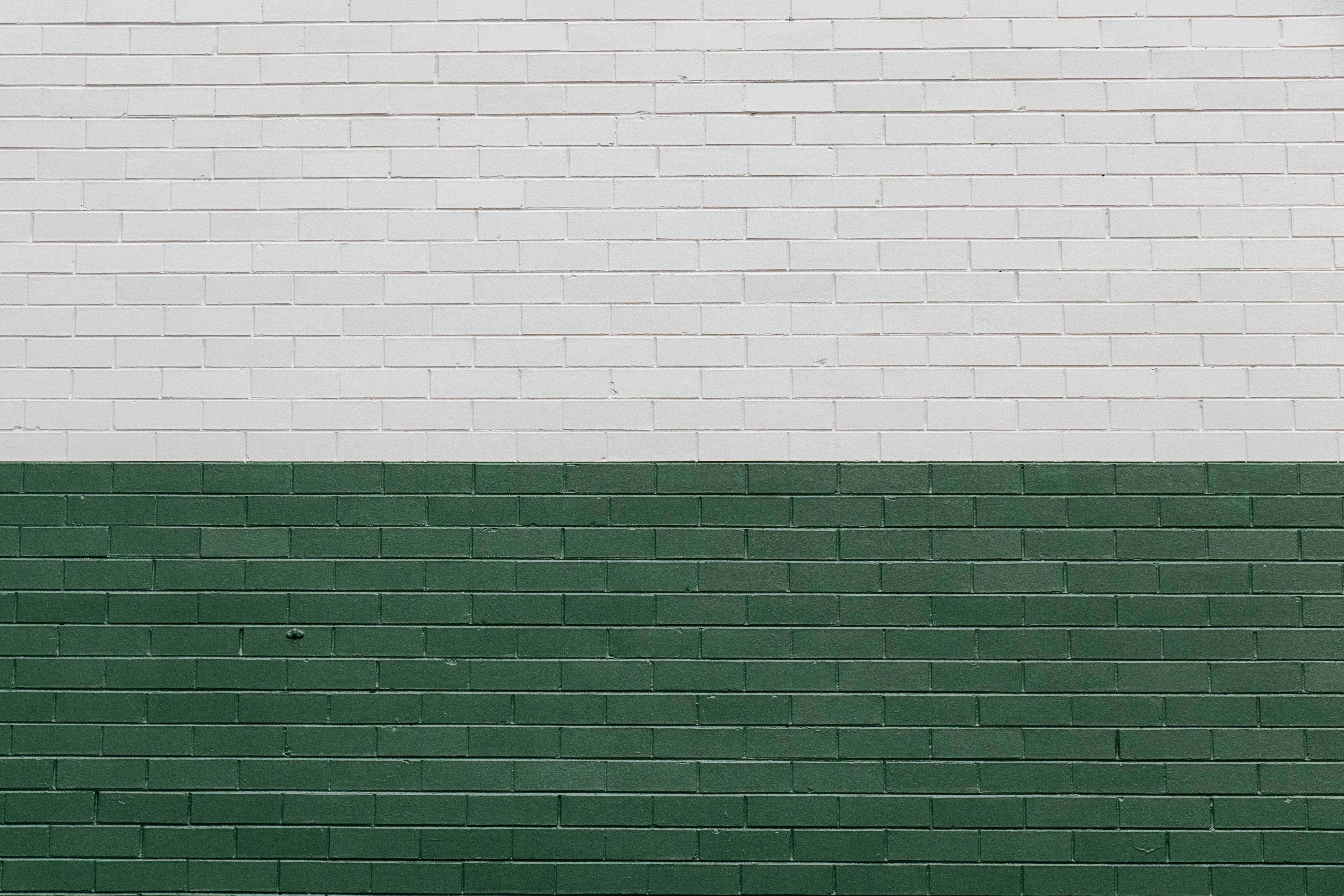 Brick Wall 桌布 壁紙 — 一面極簡主義的磚牆，一半白色一半深綠色，以乾淨的水平條紋呈現。