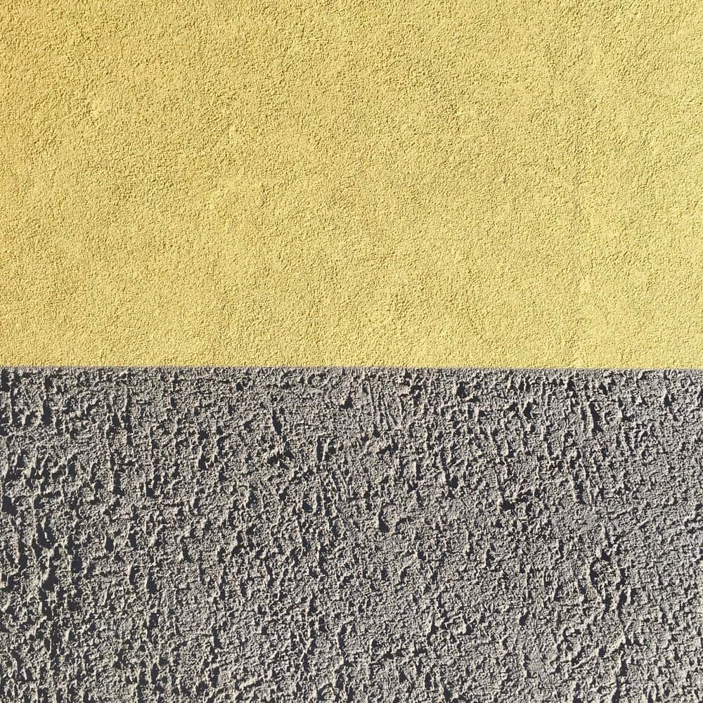 plaster 桌布 壁紙 — 一面極簡風格的牆壁，水平分割，上半部為帶紋理的芥末黃色，下半部為粗糙的灰色混凝土。