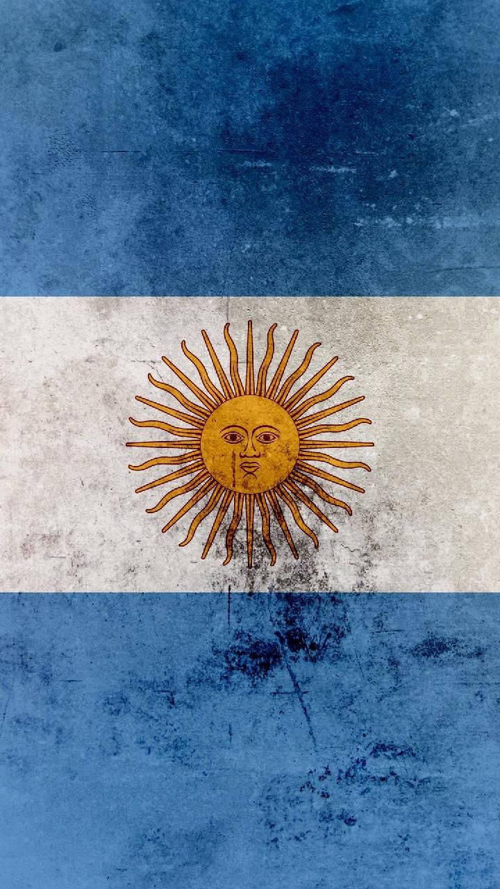 Argentina 桌布 壁紙 — 一面歷經風化的阿根廷國旗，帶有藍白條紋和金色太陽標誌，顯示出歲月和磨損的痕跡。