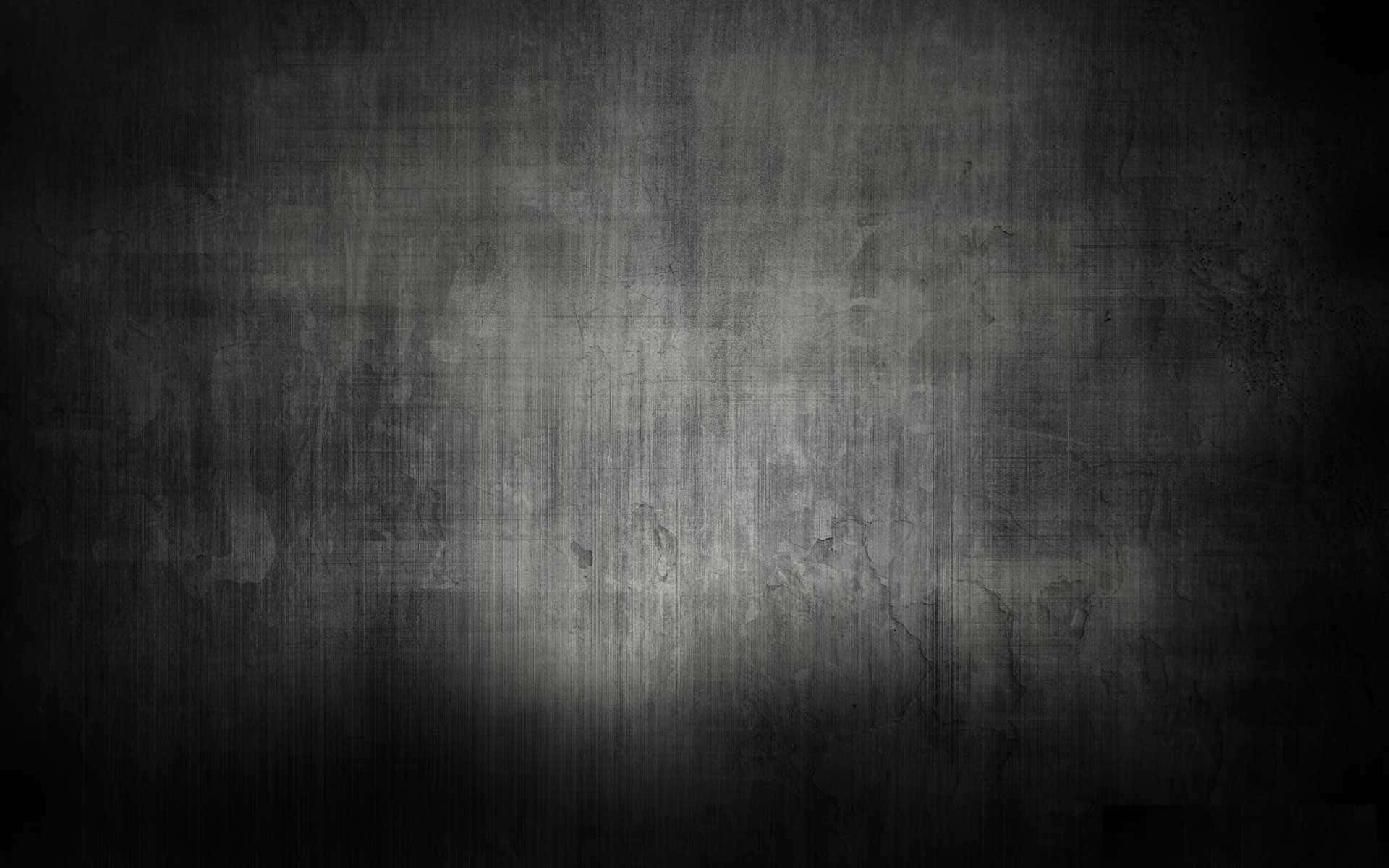 Dark Gradient 桌布 壁紙 — 一面深色紋理牆壁，中央聚光燈揭示深暗陰影中的磨損污垢和刮痕。