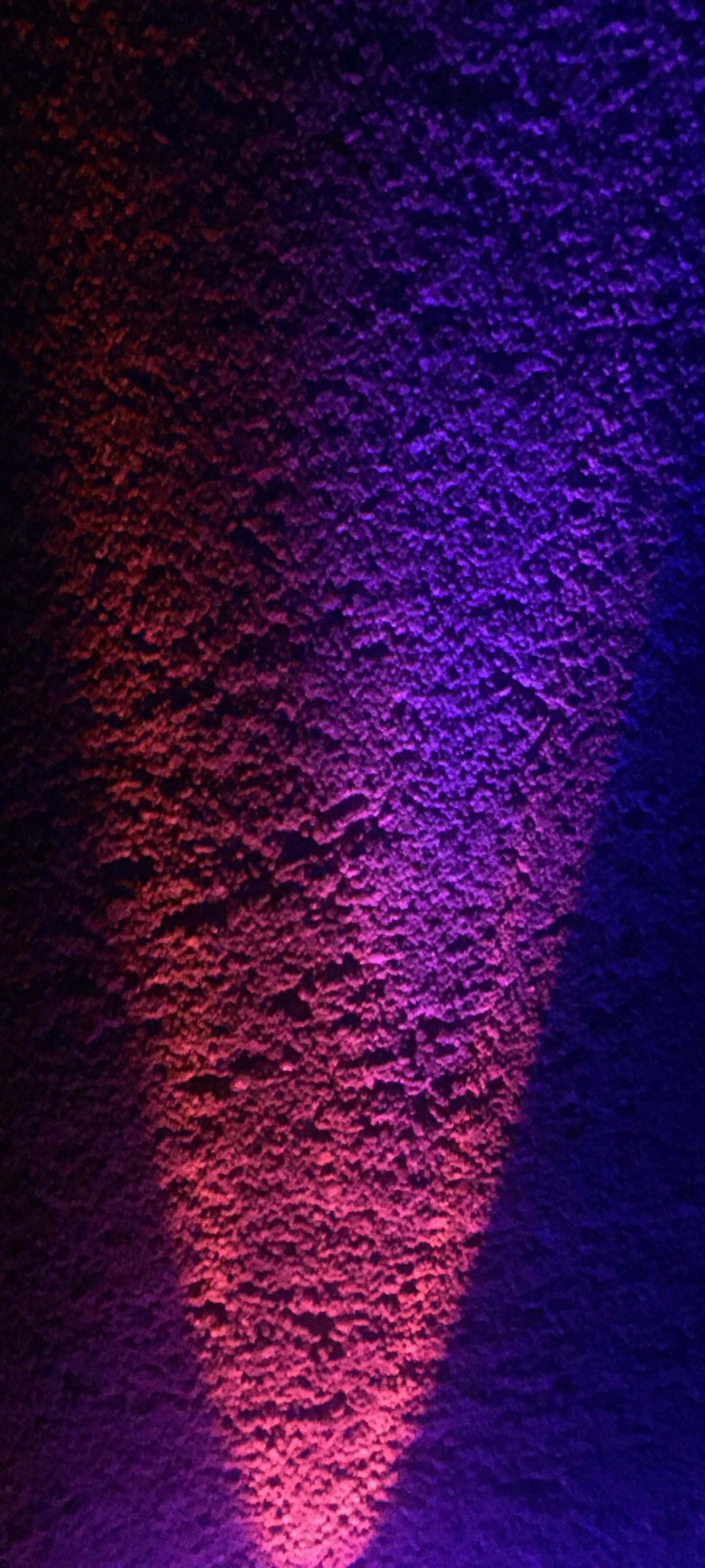 1440x3200 桌布 壁紙 — 一面紋理牆壁沐浴在紅紫漸層的鮮豔燈光中，營造出戲劇性且充滿氛圍的感覺。