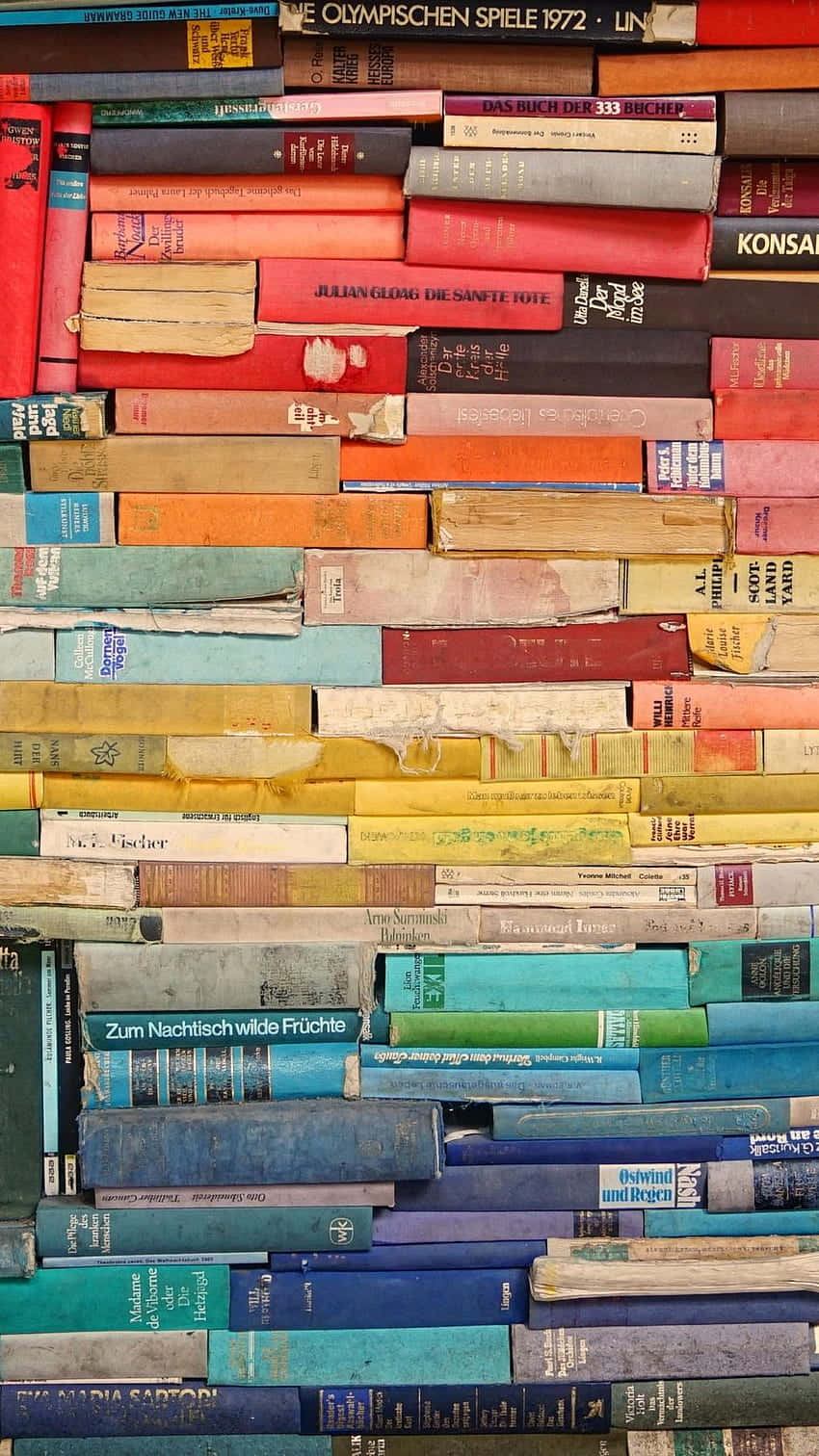 Reading 桌布 壁紙 — 一面色彩繽紛、堆疊著各種顏色和磨損書脊的復古書籍牆，創造出有質感的文學拼貼畫。