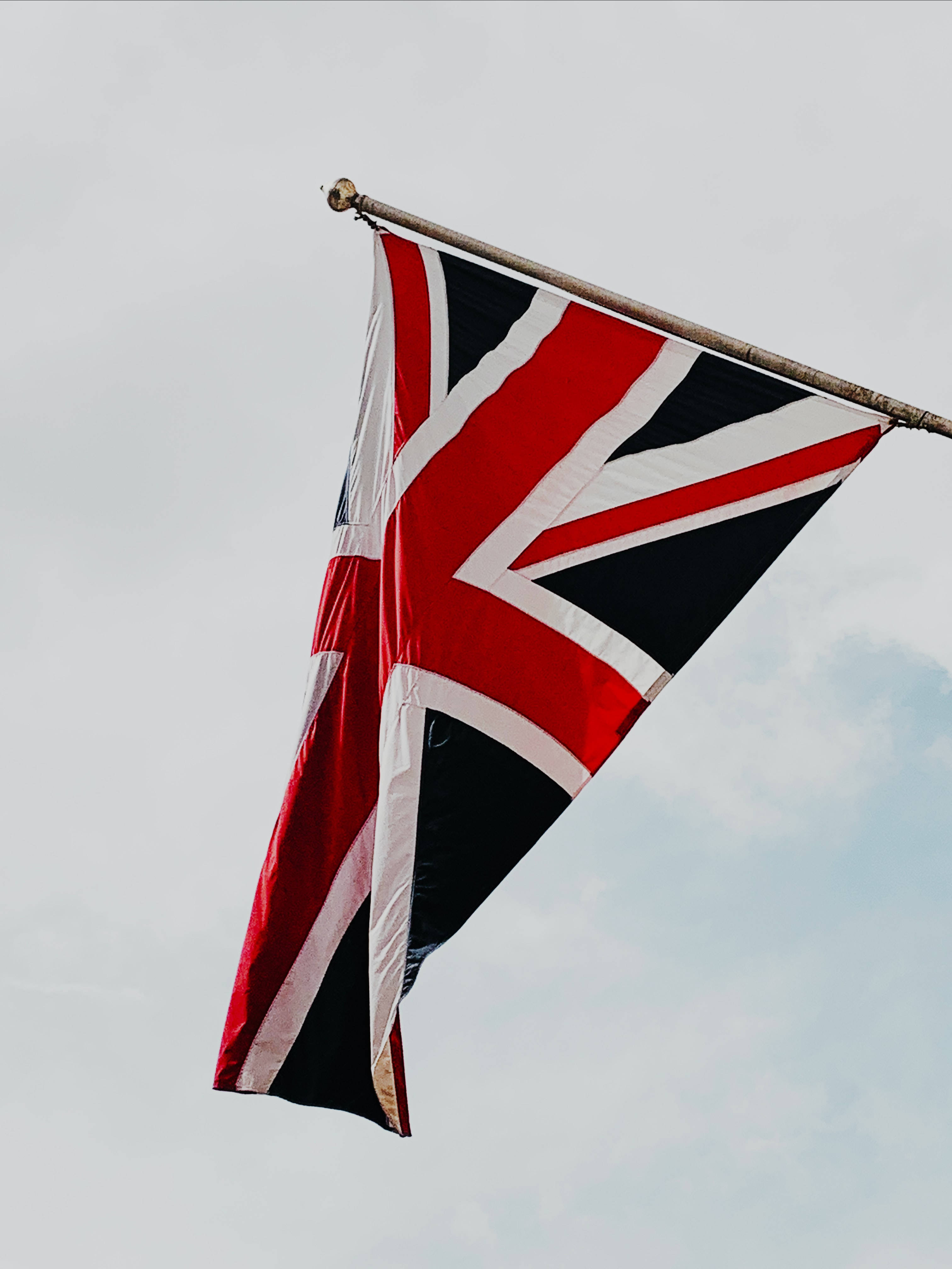 England 桌布 壁紙 — 一面英國國旗在柔和的多雲天空下，帶有細微雲紋，動態飄揚。