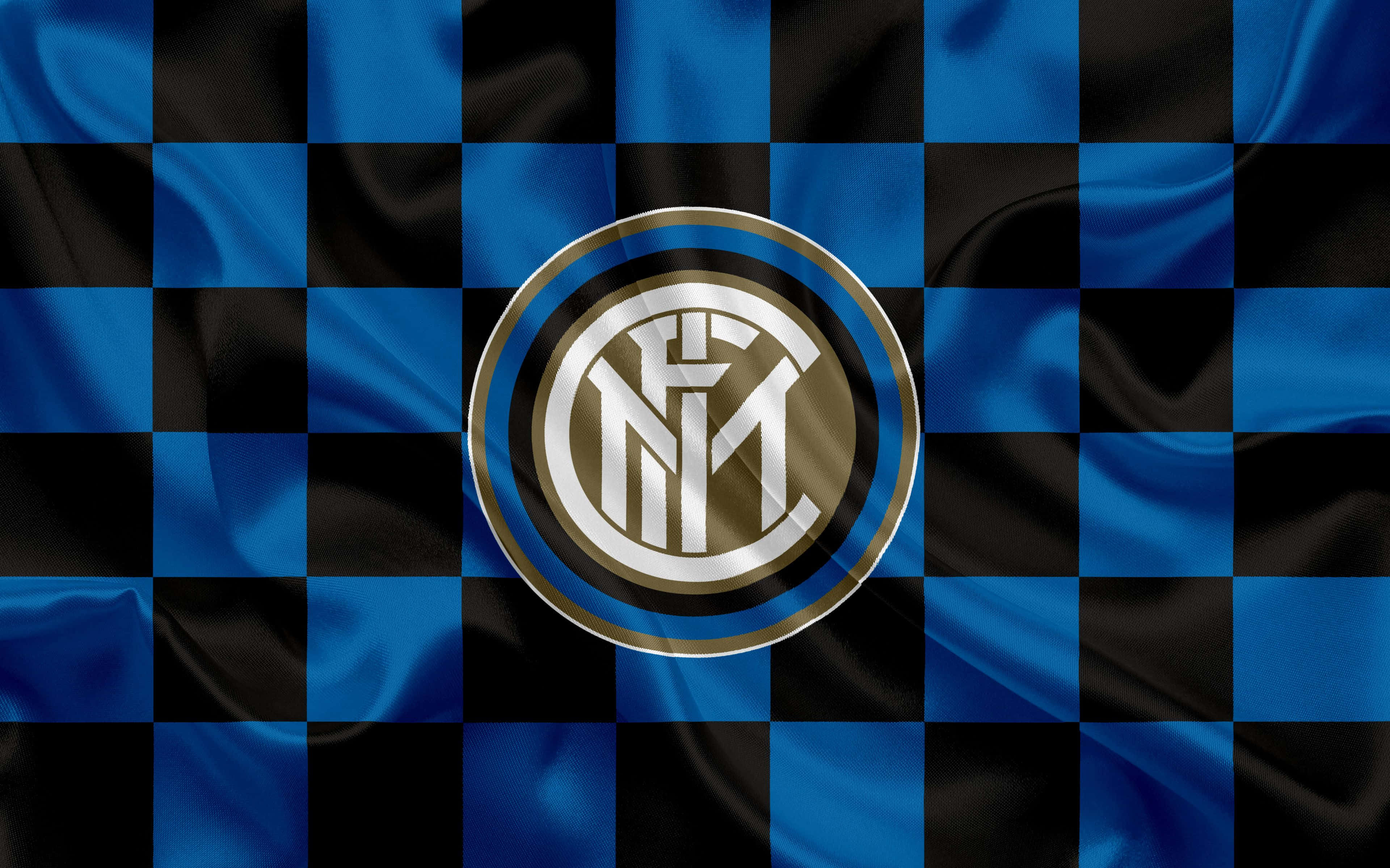 Inter Milan 桌布 壁紙 — 一面隨風飄揚的藍黑格子旗，中央的國際米蘭會徽在燈光下閃閃發光。