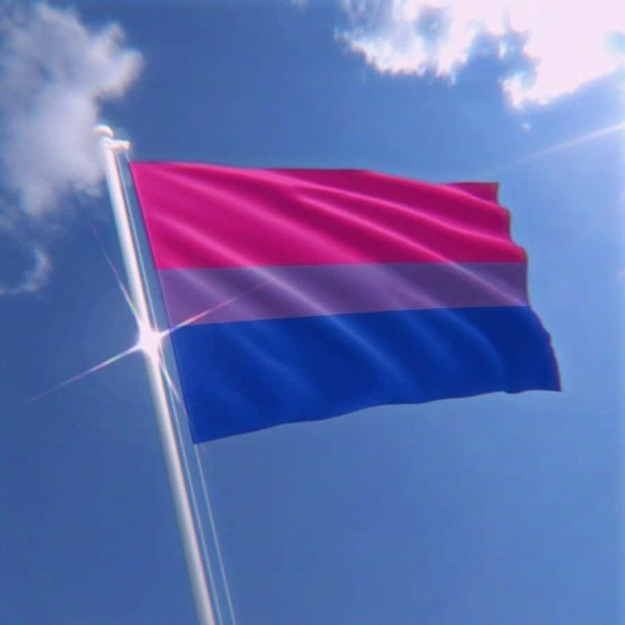 Bi Flag 桌布 壁紙 — 一面雙性戀驕傲旗幟在晴朗藍天、 fluffy 白雲和陽光下自豪地飄揚。