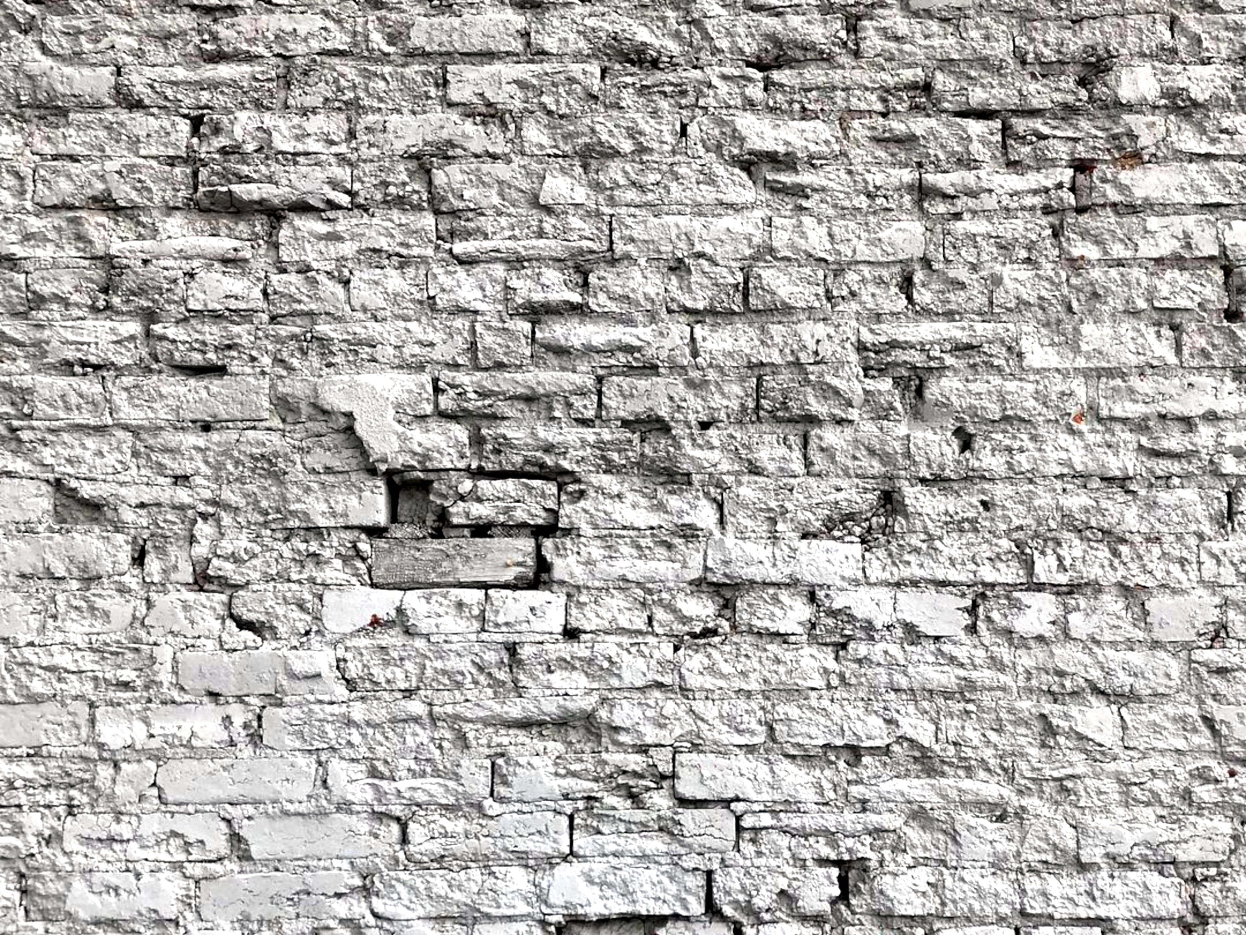 White Brick Wall 桌布 壁紙 — 一面風化的白色磚牆，帶有裂開的灰泥和暴露的砂漿，顯示出歲月和破損。