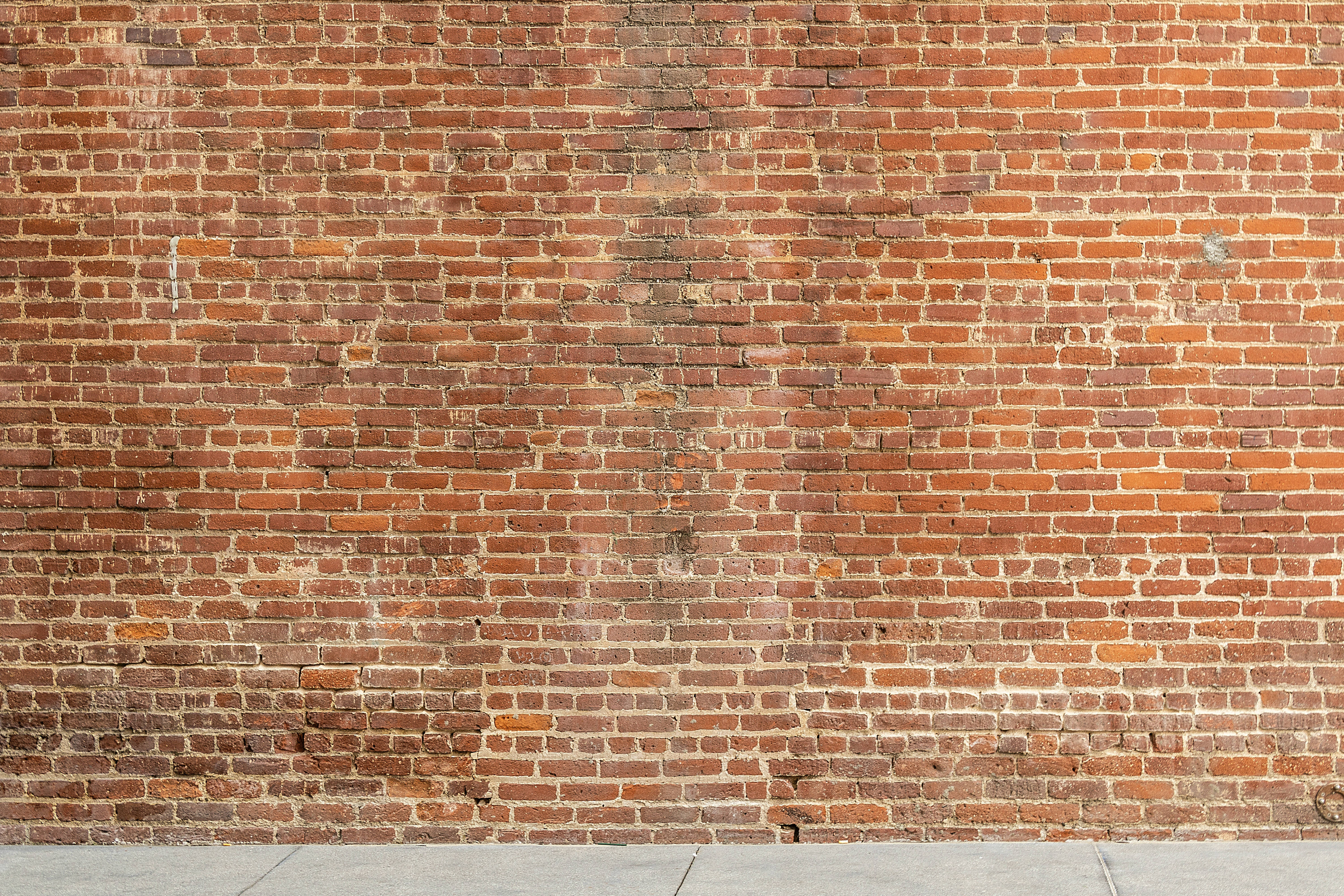 Brick Wall 桌布 壁紙 — 一面風化的紅磚牆，在明亮日光下呈現多種色調和灰縫線。