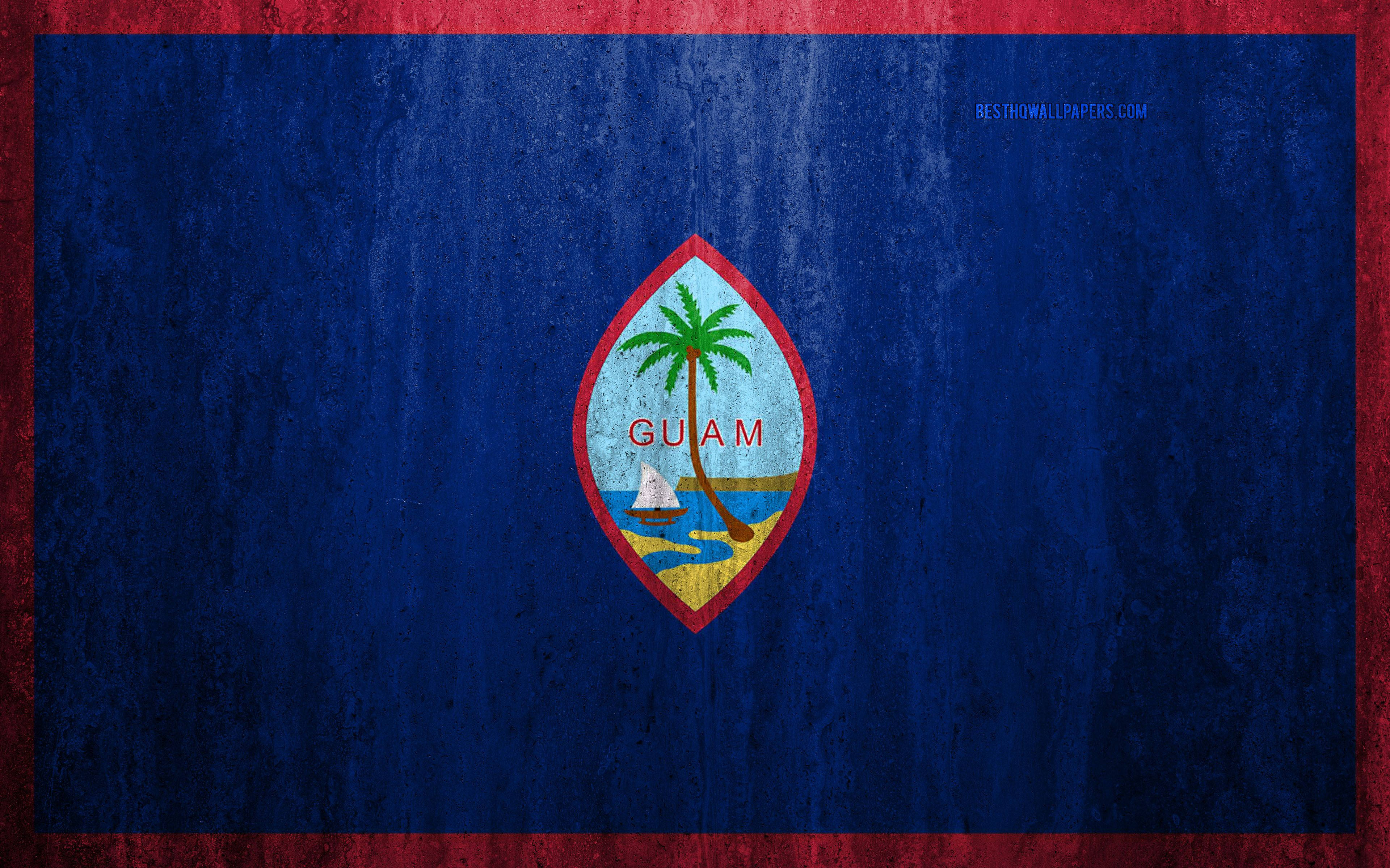 Guam 桌布 壁紙 — 一面風化的關島旗幟，中央有棕櫚樹帆船和島嶼的標誌，藍色背景上鑲有紅色邊框。