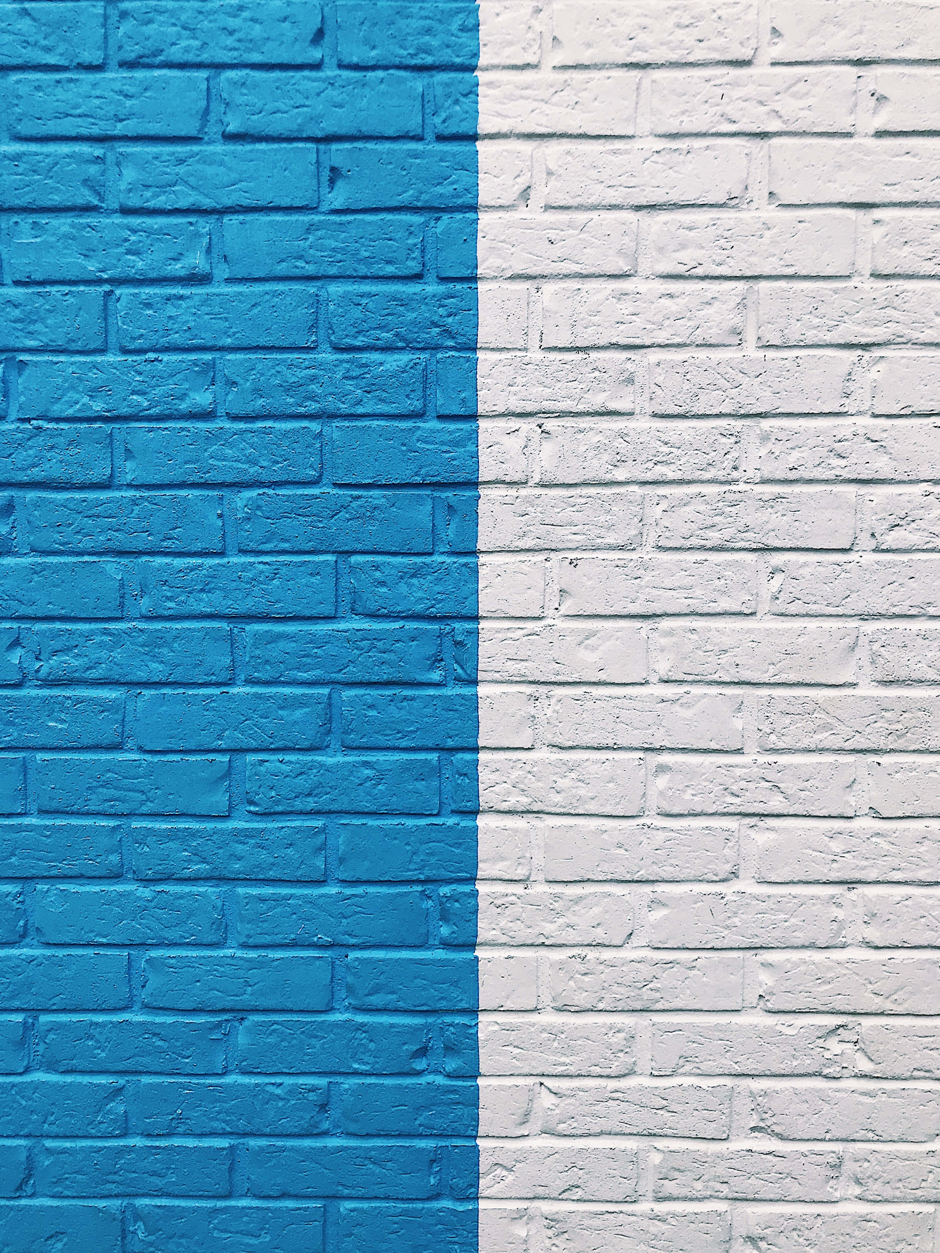 Brick Wall 桌布 壁紙 — 一面鮮明劃分的磚牆，一半塗上大膽的藍色，一半塗上純淨的白色，營造出極簡的幾何對比。
