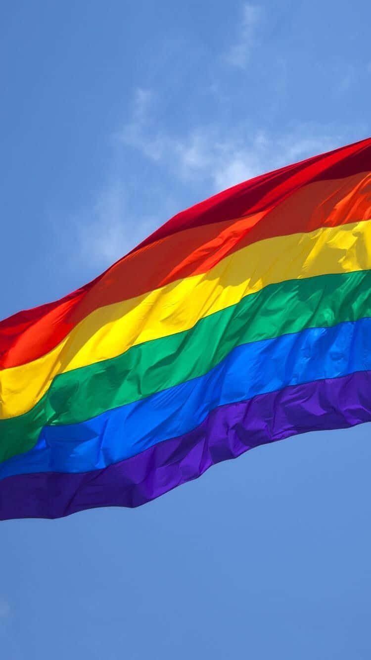 Lgbt Phone 桌布 壁紙 — 一面鮮豔的彩虹旗在晴朗藍天和薄雲中動態飄揚。