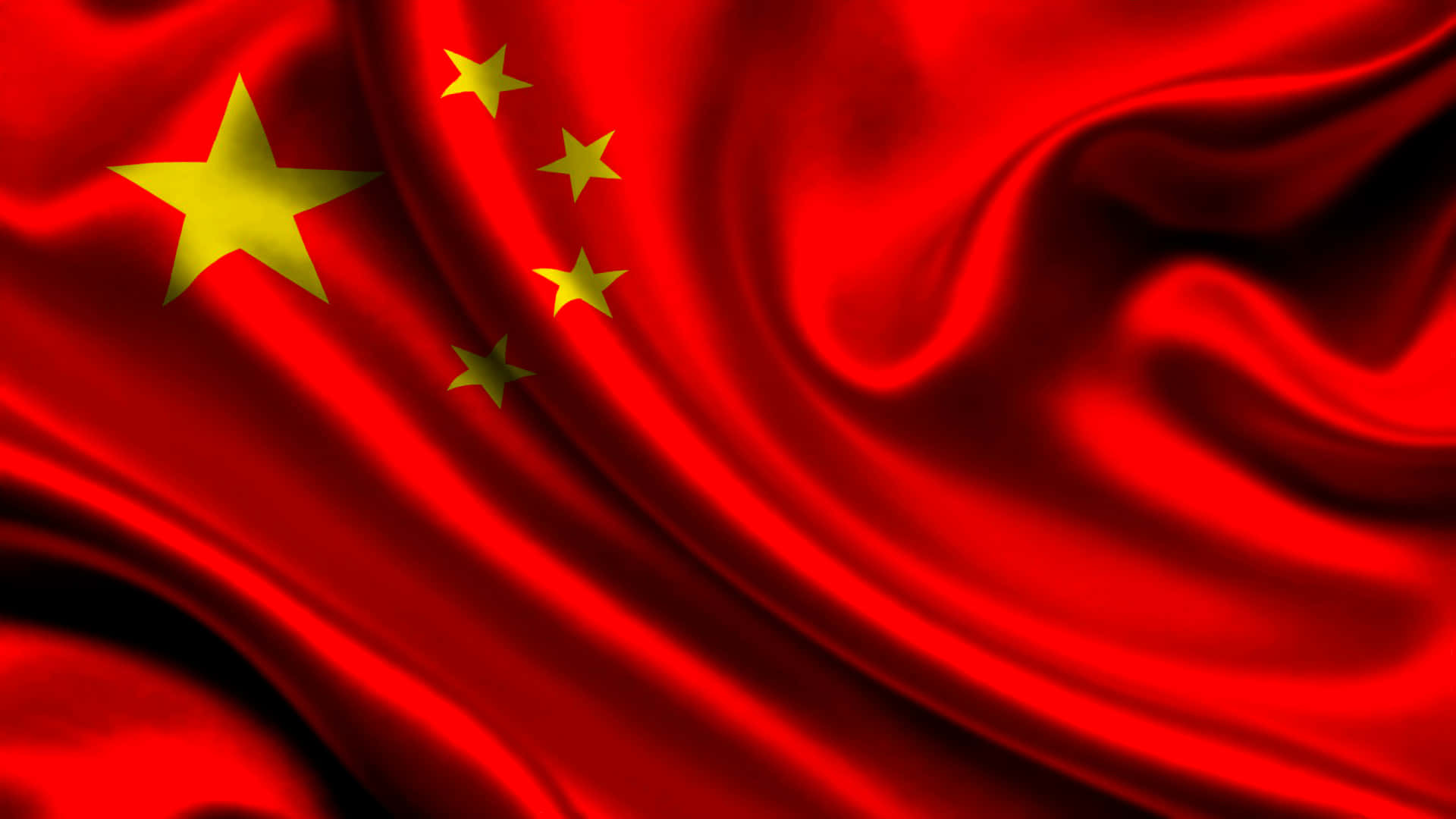 中國 桌布 壁紙 — 一面鮮豔的紅色中國國旗，金色星星在戲劇性燈光下於豐富的布料褶皺中動態飄揚。