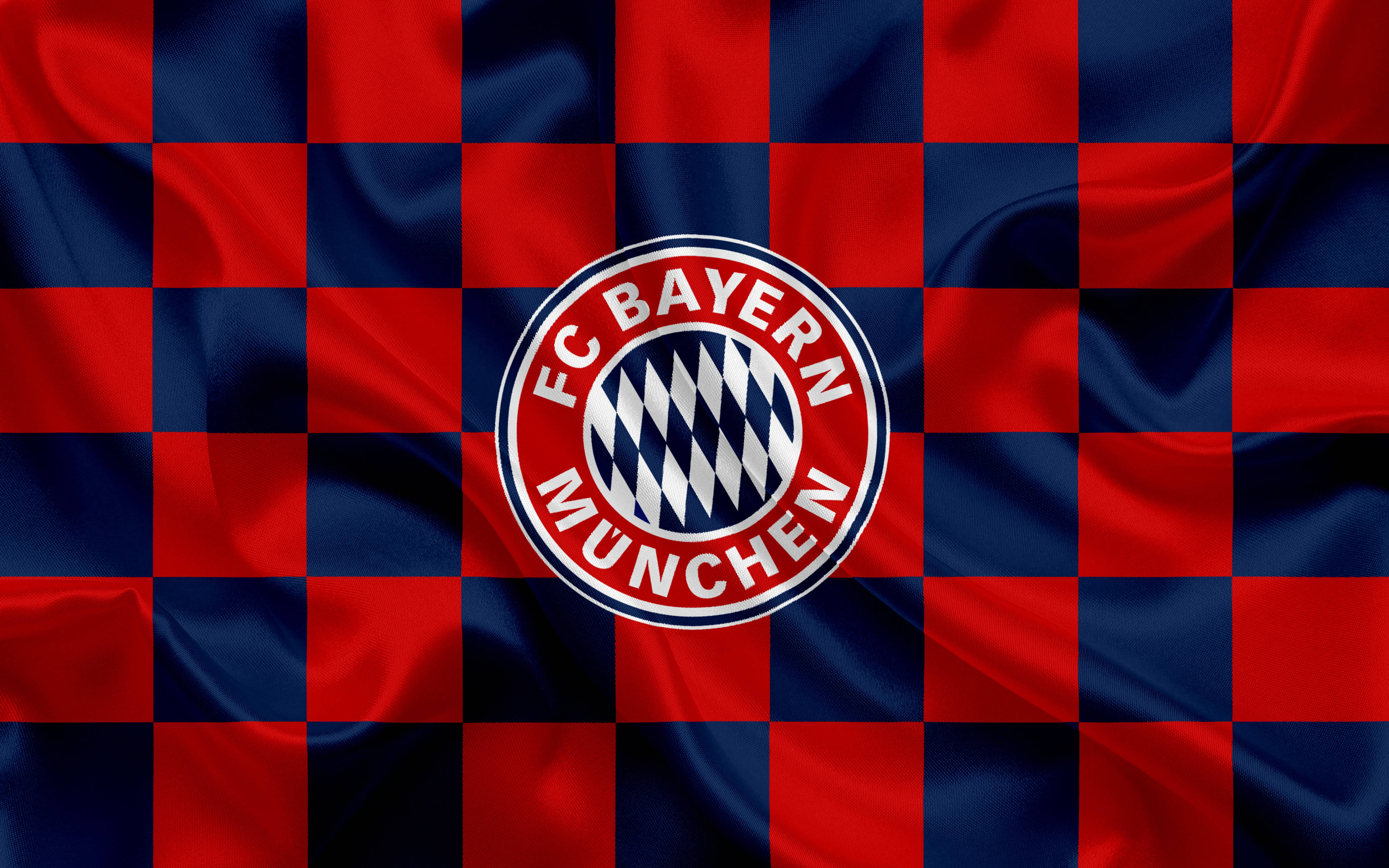Bayern 桌布 壁紙 — 一面鮮豔的紅藍格子旗，中央有拜仁慕尼黑隊徽，布料呈波浪狀。