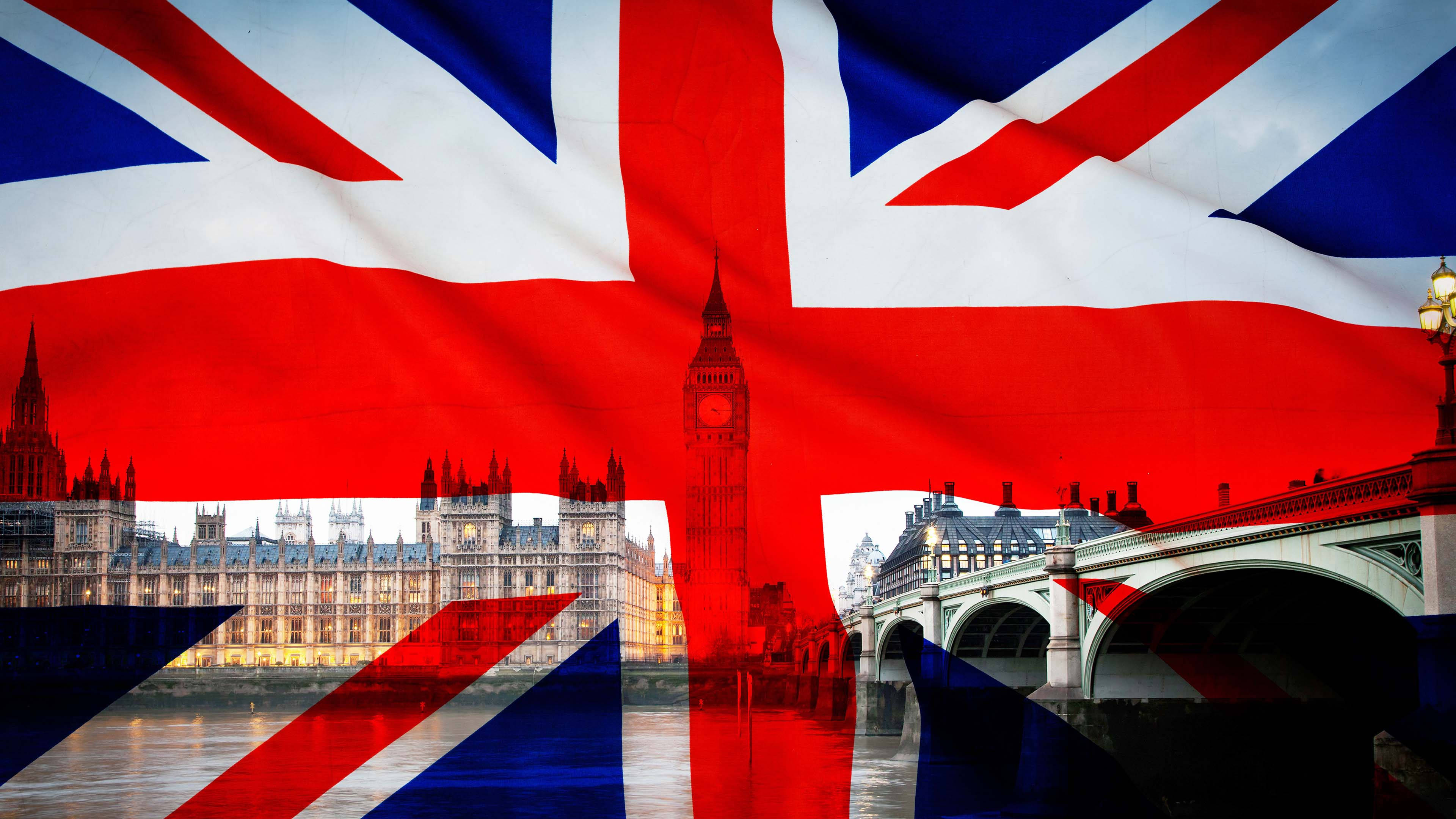 United Kingdom Flag 桌布 壁紙 — 一面鮮豔的英國國旗覆蓋著黃昏時分倫敦天際線，包括大笨鐘和西敏橋。