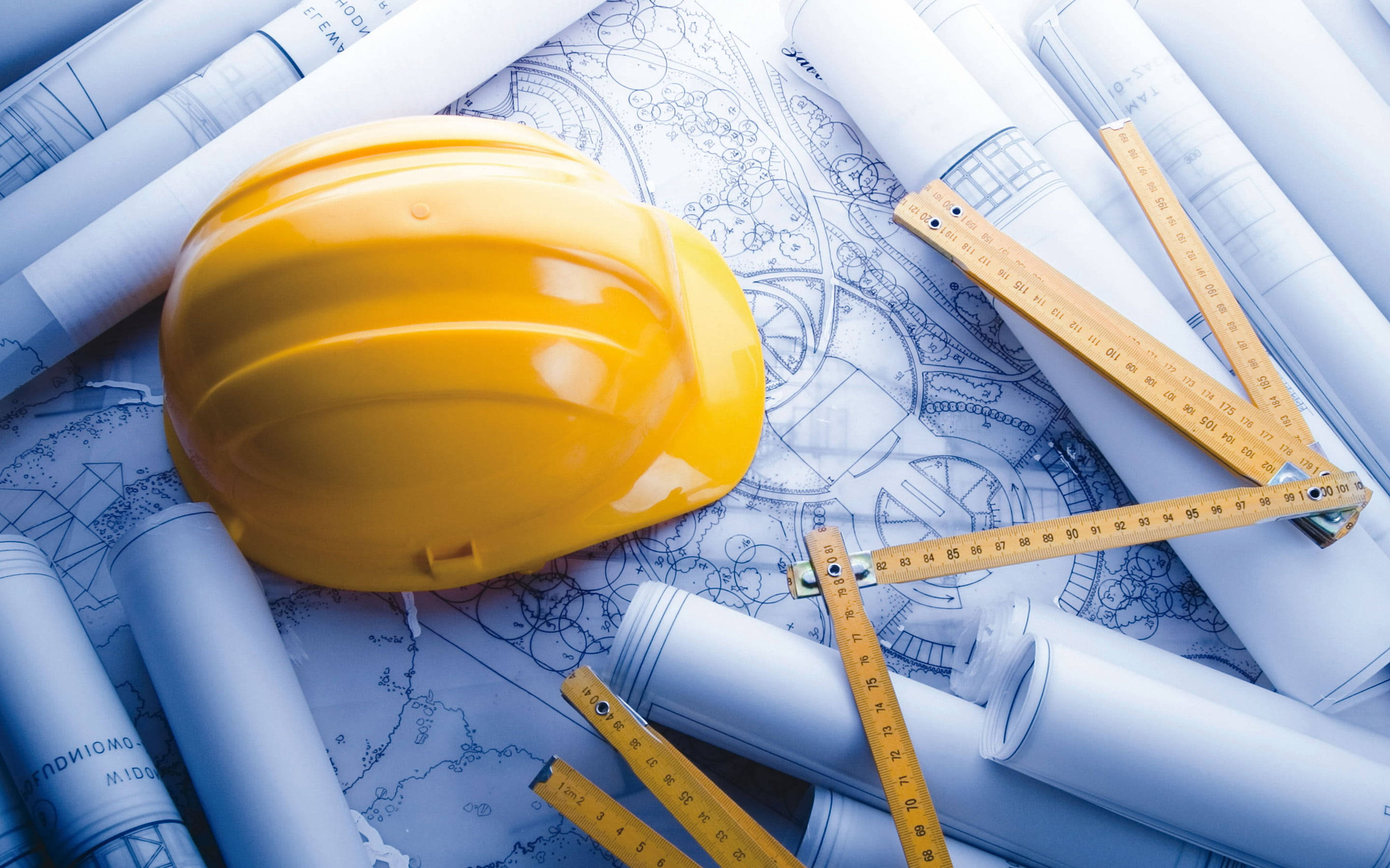 建築 桌布 壁紙 — 一頂亮黃色的安全帽放在建築規劃表面的藍圖和木尺上。