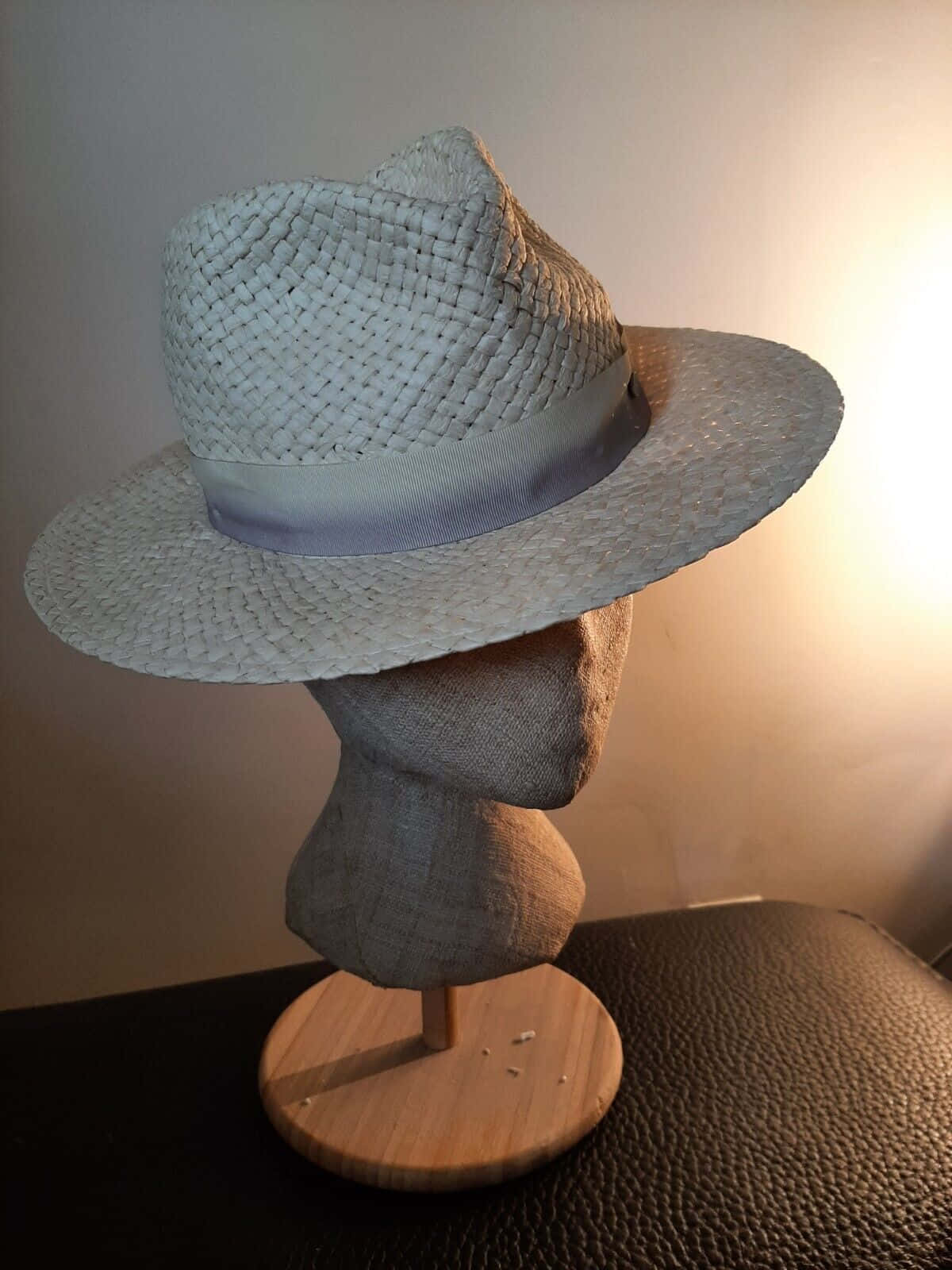 Clothes 桌布 壁紙 — 一頂淺灰色編織草帽，飾有薰衣草色絲帶，展示在帶紋理的人體模型頭上，背景是柔和照明的牆壁。