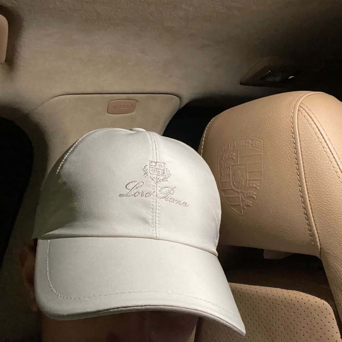 Cap 桌布 壁紙 — 一頂白色Loro Piana帽放在米色皮革汽車座椅上，旁邊是保時捷頭枕標誌。