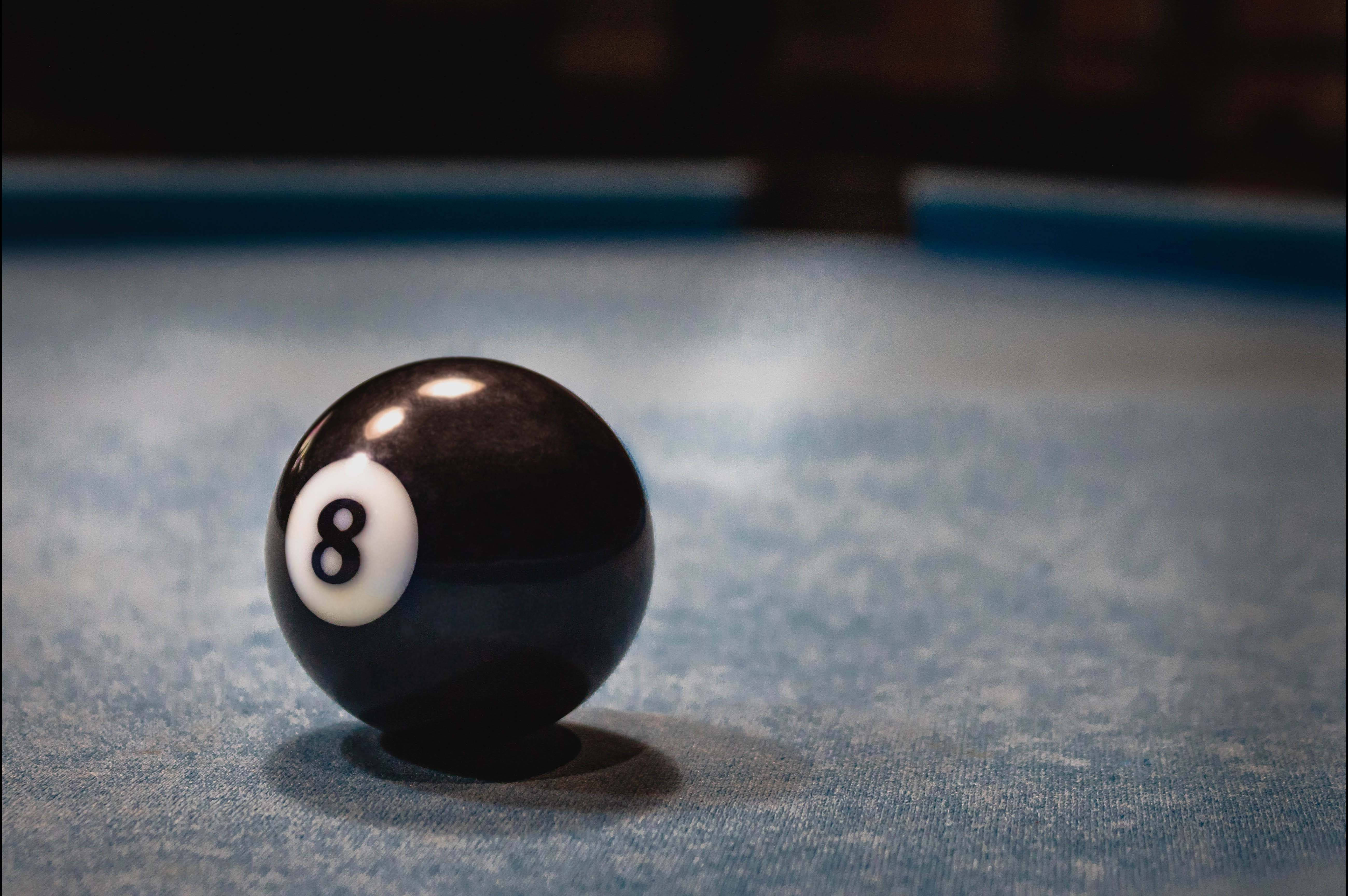 Snooker 桌布 壁紙 — 一顆亮面黑色8號球置於有紋理的藍色撞球桌中央，光線柔和。