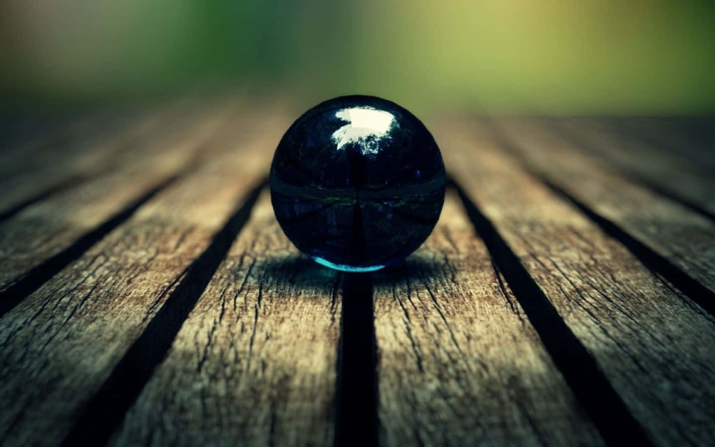 Crystal Ball 桌布 壁紙 — 一顆亮面黑色玻璃球放置在經風化的木板上，背景柔和散景。