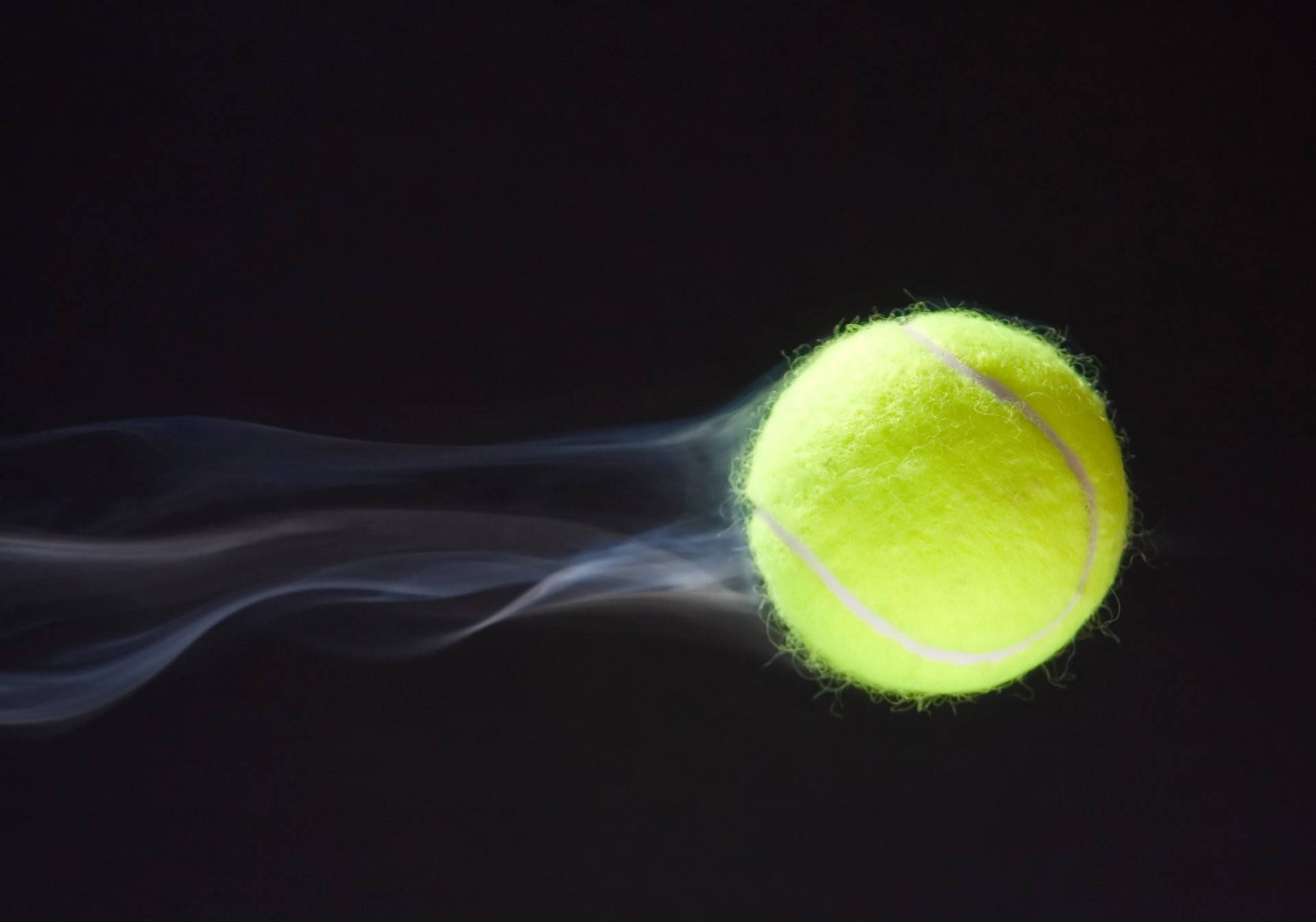 Tennis 桌布 壁紙 — 一顆亮黃色的網球劃破黑暗，留下一縷輕煙。