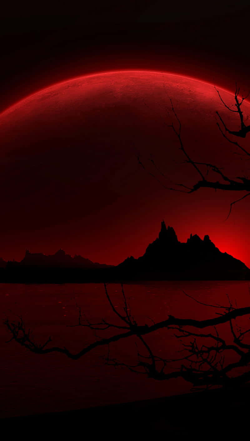 Mountain Silhouette 桌布 壁紙 — 一顆令人不安的紅色星球籠罩在黑暗的景觀之上，襯著深紅色的天空，有剪影般的山脈和光禿的樹枝。