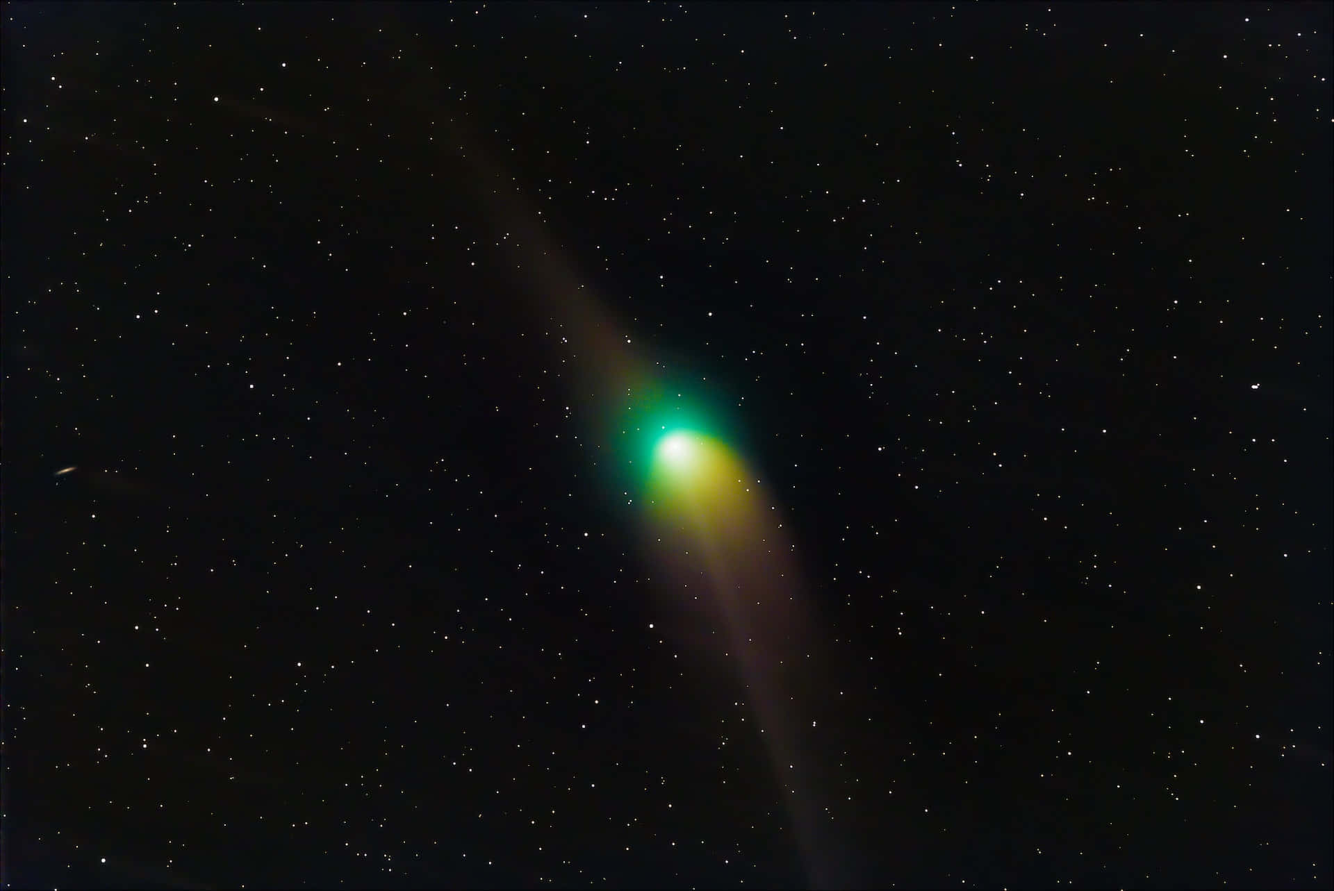 comet 桌布 壁紙 — 一顆充滿活力的綠色和黃色彗星，拖著發光的尾巴劃過繁星點點的夜空。