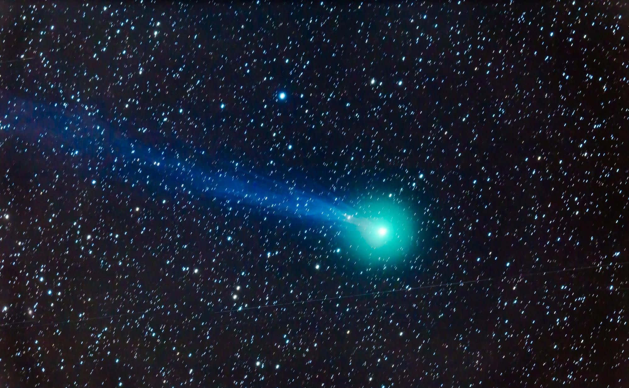 comet 桌布 壁紙 — 一顆充滿活力的綠色彗星拖著發光的藍色尾巴，劃過深邃黑色宇宙背景下的星場。