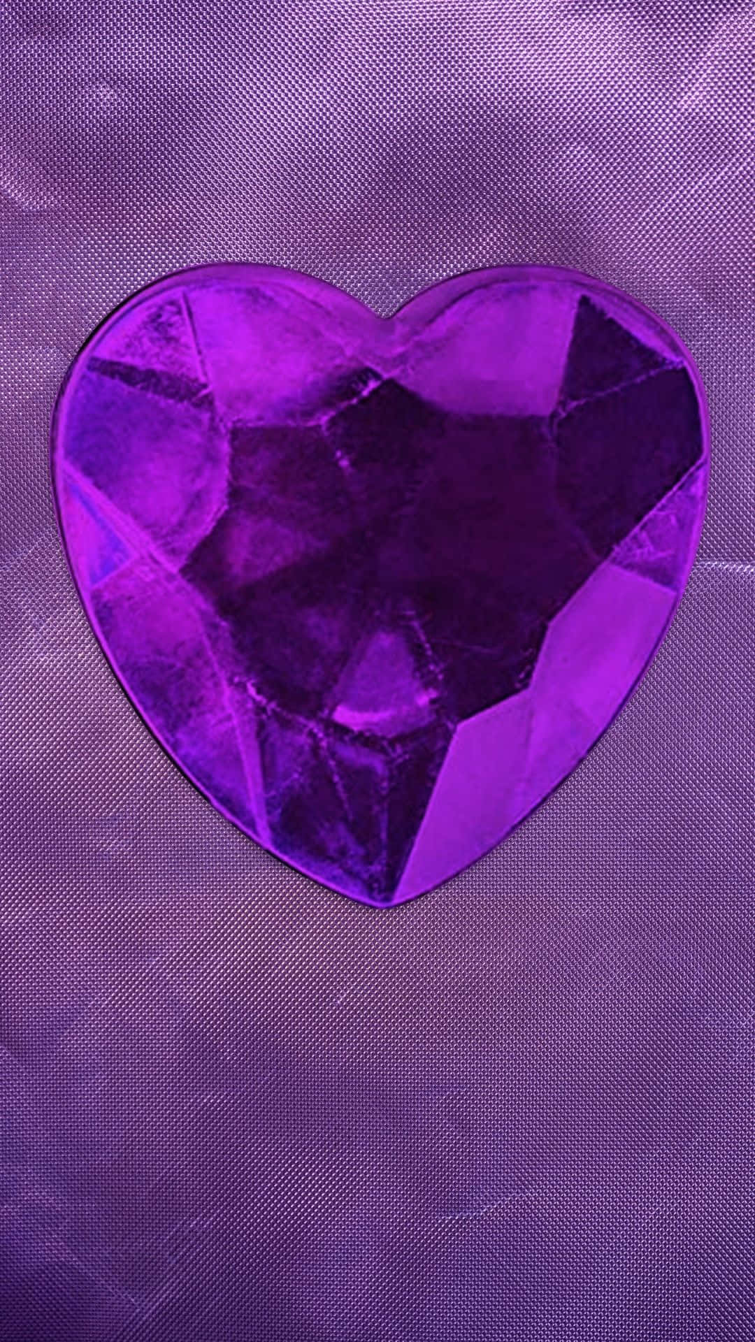 Heart 桌布 壁紙 — 一顆切割面紫色心形寶石放置在紋理紫色布料背景上。