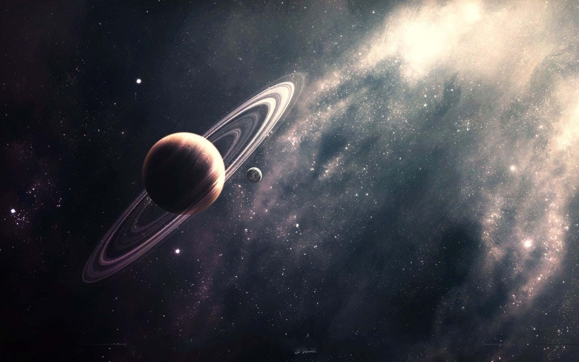 土星 桌布 壁紙 — 一顆壯麗的環狀行星伴隨著一顆小衛星，在深空中圍繞著發光的星雲和星場運行。