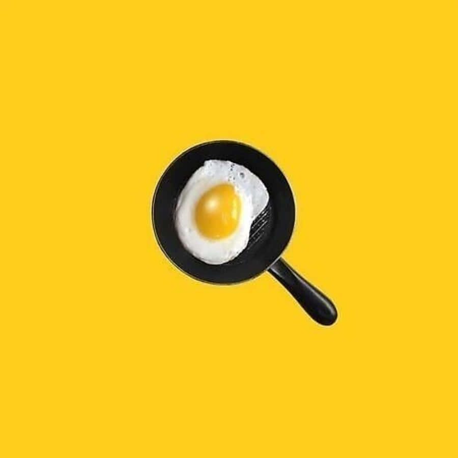 Egg 桌布 壁紙 — 一顆完美煎好的太陽蛋放在一個黑色小煎鍋裡，背景是鮮黃色。