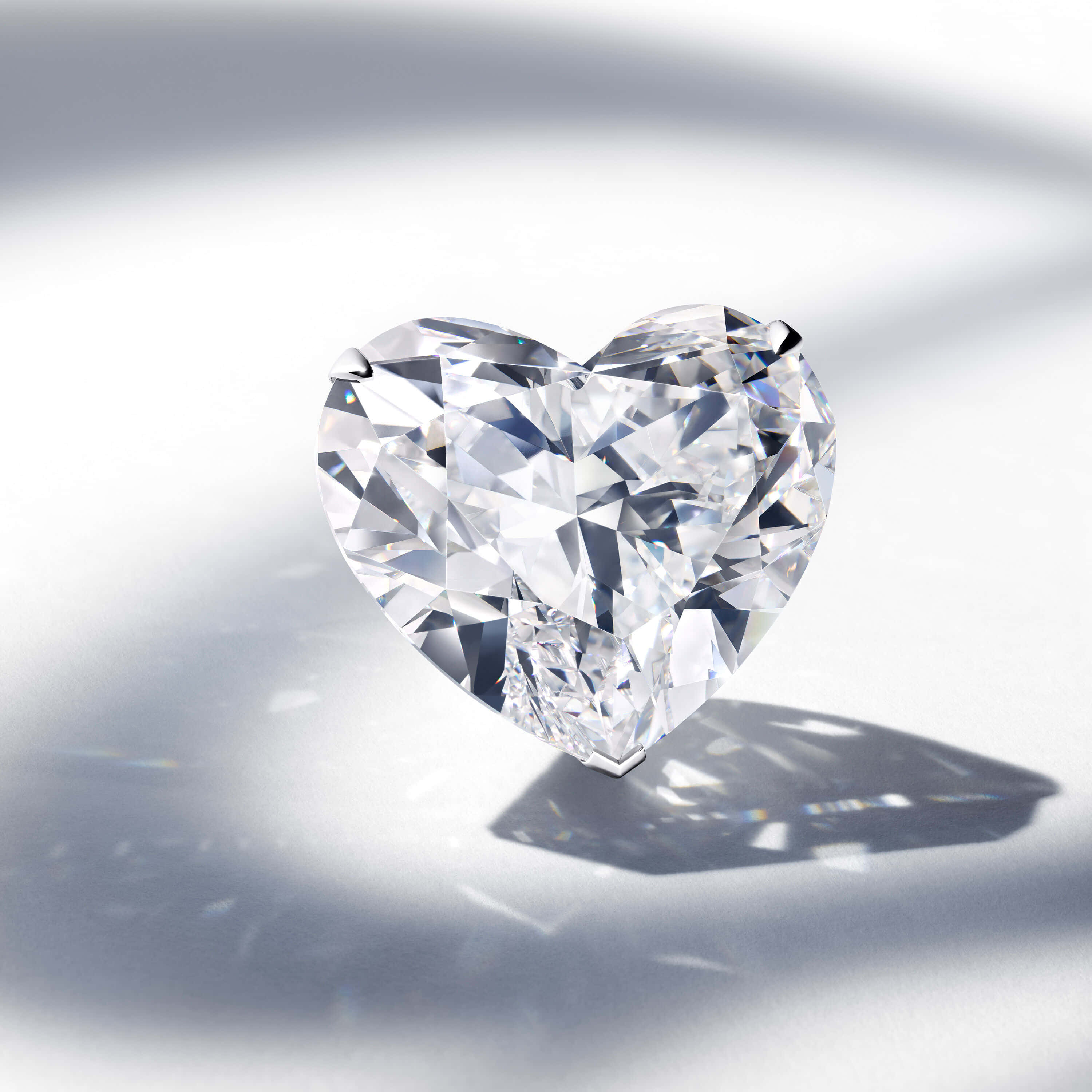 diamonds 桌布 壁紙 — 一顆完美的心形鑽石在柔軟的白色表面上閃耀著銳利的刻面和燦爛的反射。