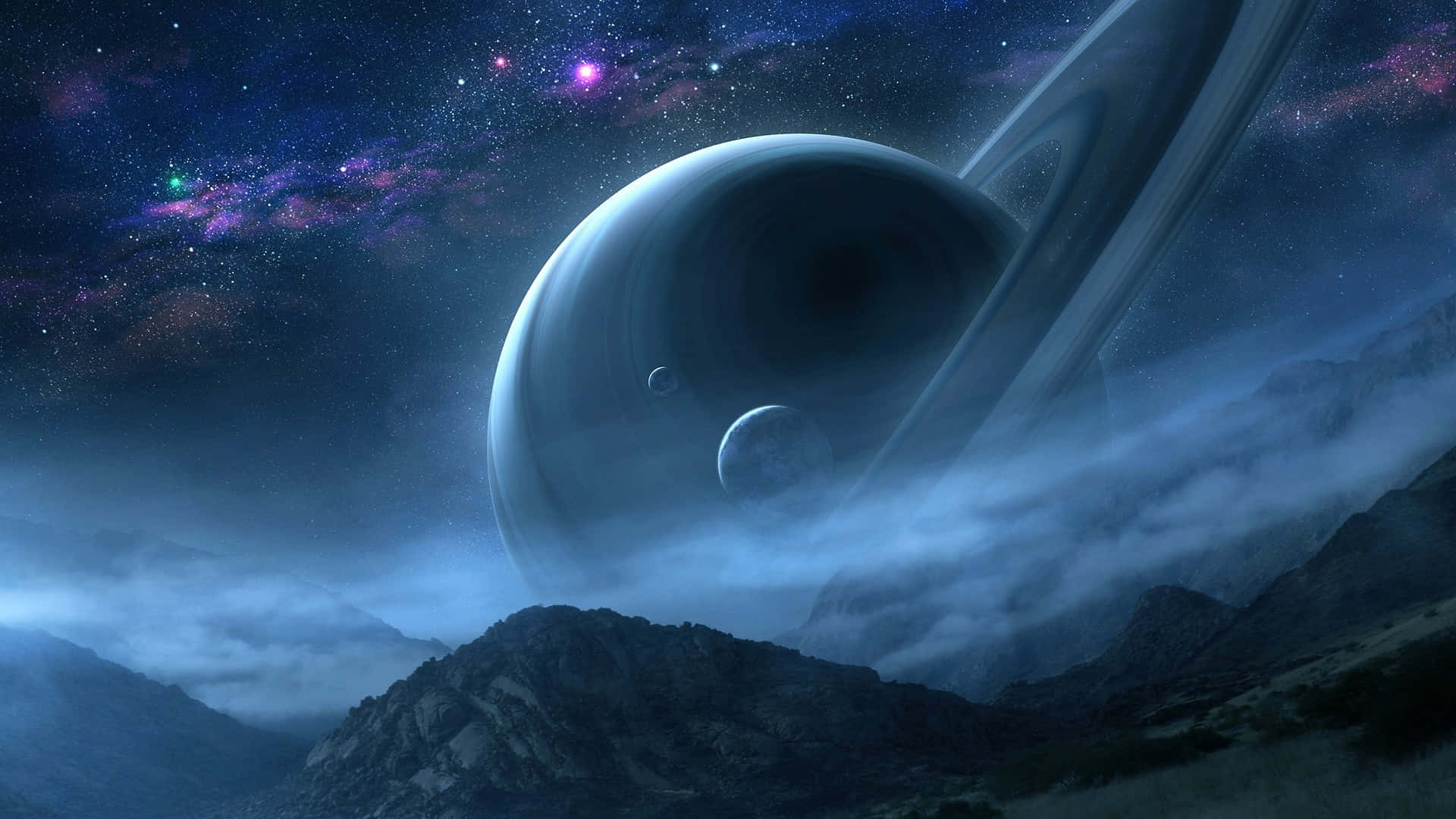 土星 桌布 壁紙 — 一顆巨大的環狀行星在充滿活力的星雲天空下，聳立於霧氣籠罩的山脈之上。
