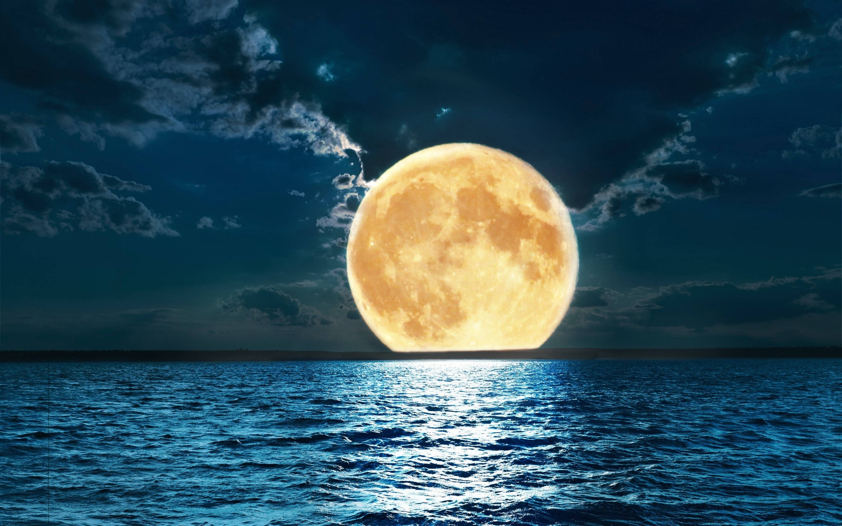 Beautiful Full Moon 桌布 壁紙 — 一顆巨大的發光滿月在多雲的夜空下從深藍色的海洋上升起。