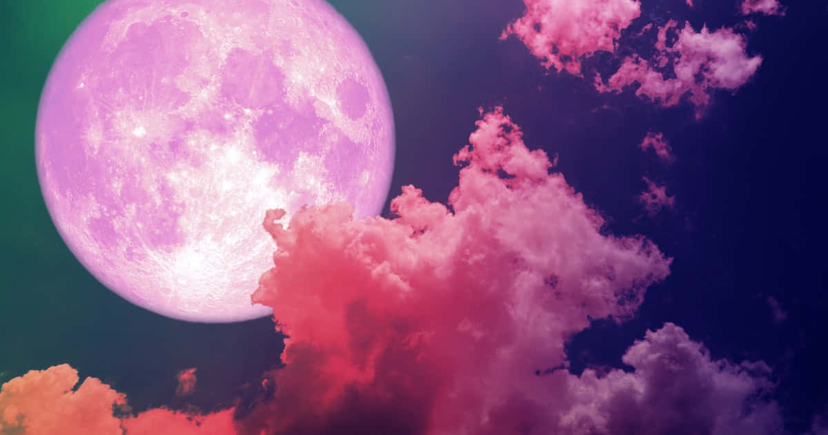 Pink Moon Real 桌布 壁紙 — 一顆巨大的發光粉紅色月亮照亮了深紫色天空下鮮豔的粉紅色和橙色雲彩。
