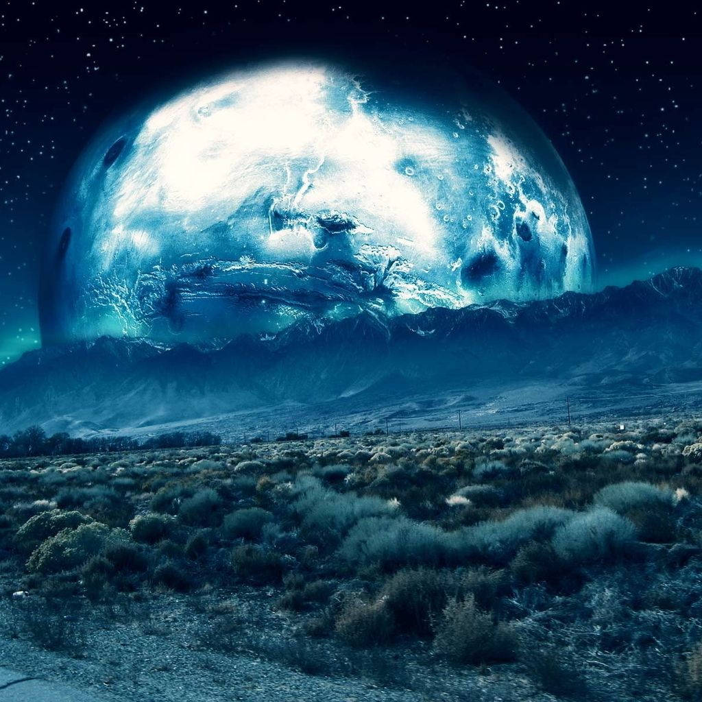外星沙漠景觀，夜間有一顆巨大的藍色發光行星從山脈上升起。 — iPad mini 動態圖片 壁紙