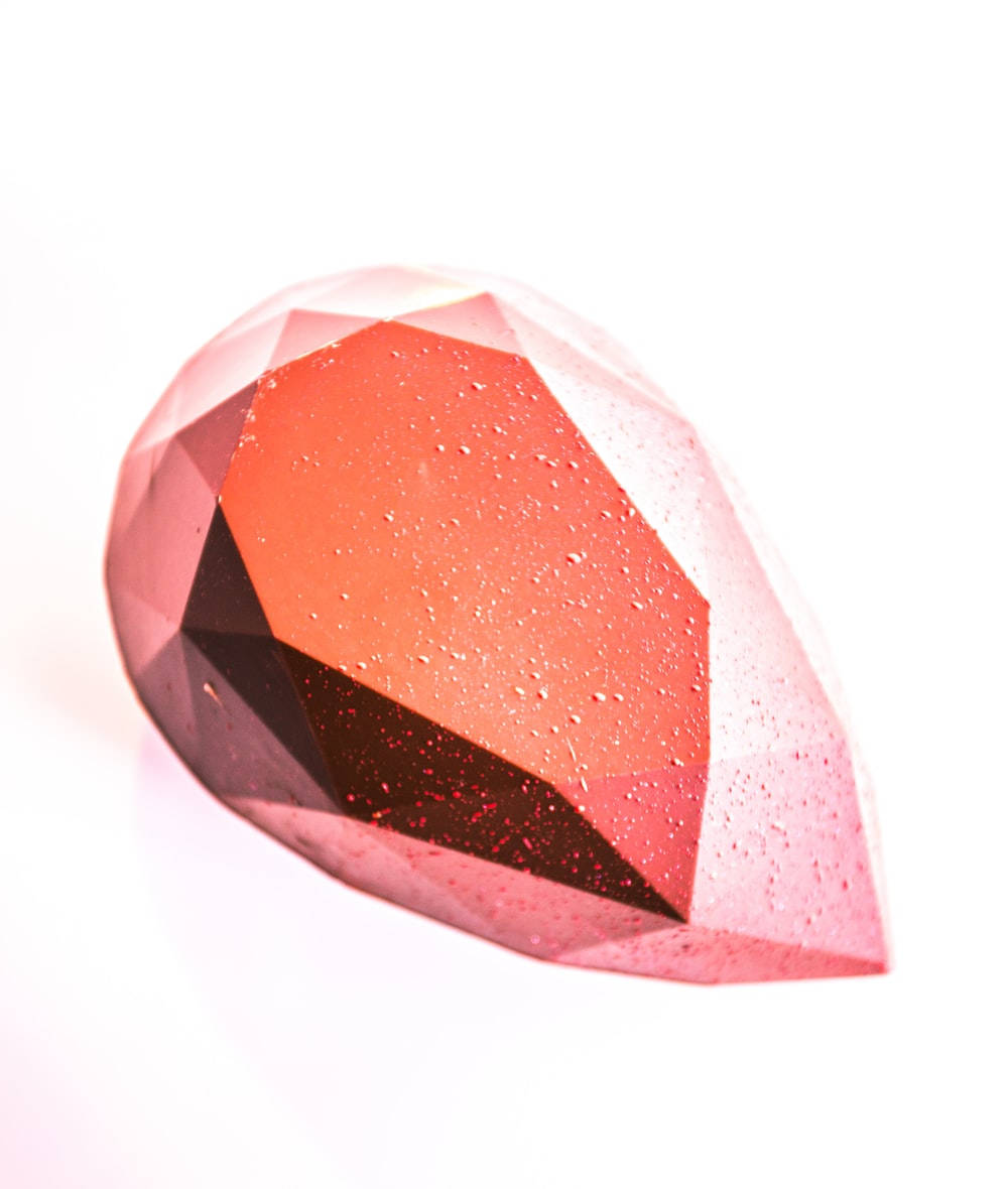 Red Crystal 桌布 壁紙 — 一顆帶有水滴的切割粉紅寶石在純白背景下閃閃發光。