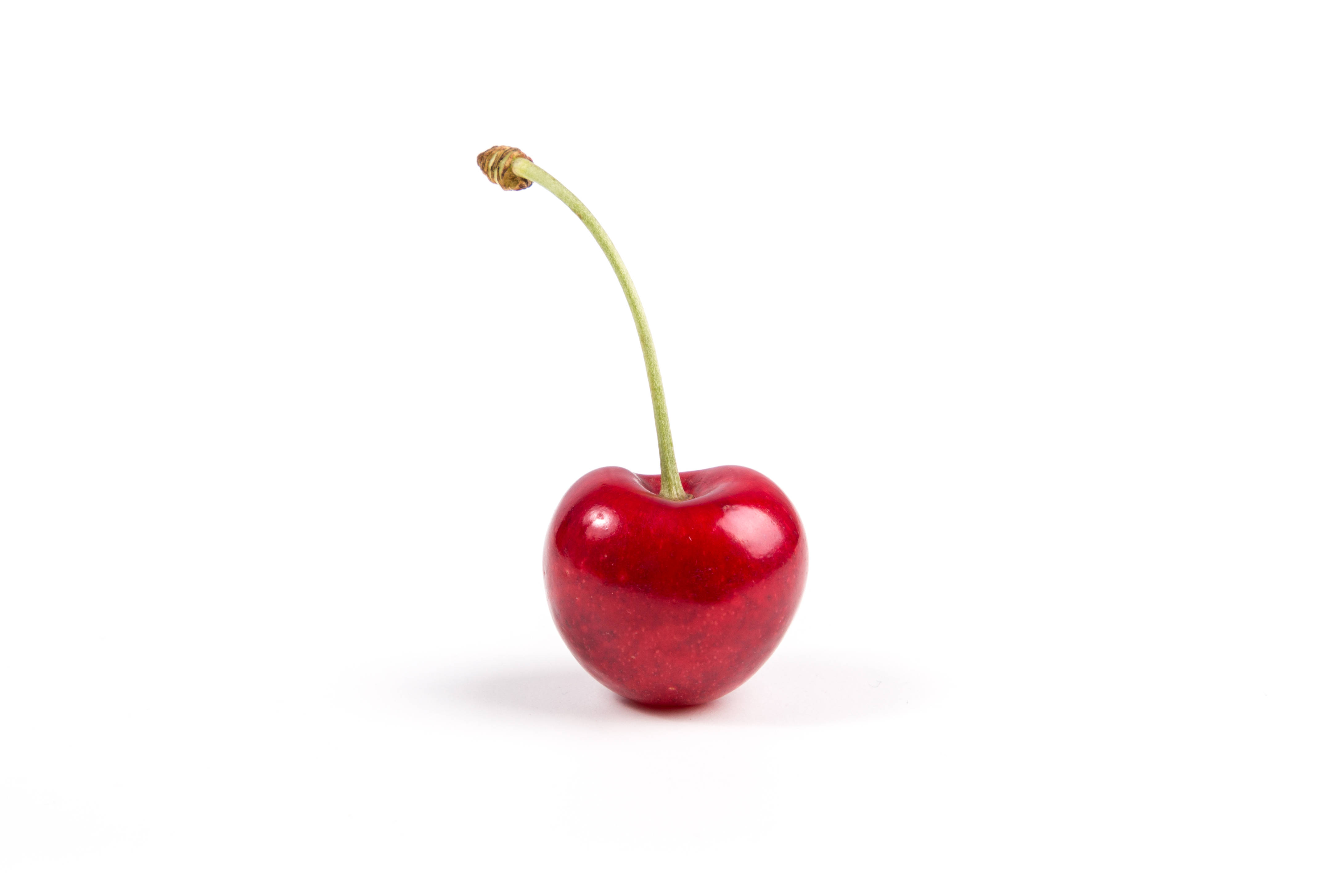 Cherry 桌布 壁紙 — 一顆帶有綠色莖的亮紅色櫻桃，孤立在純白色背景上。