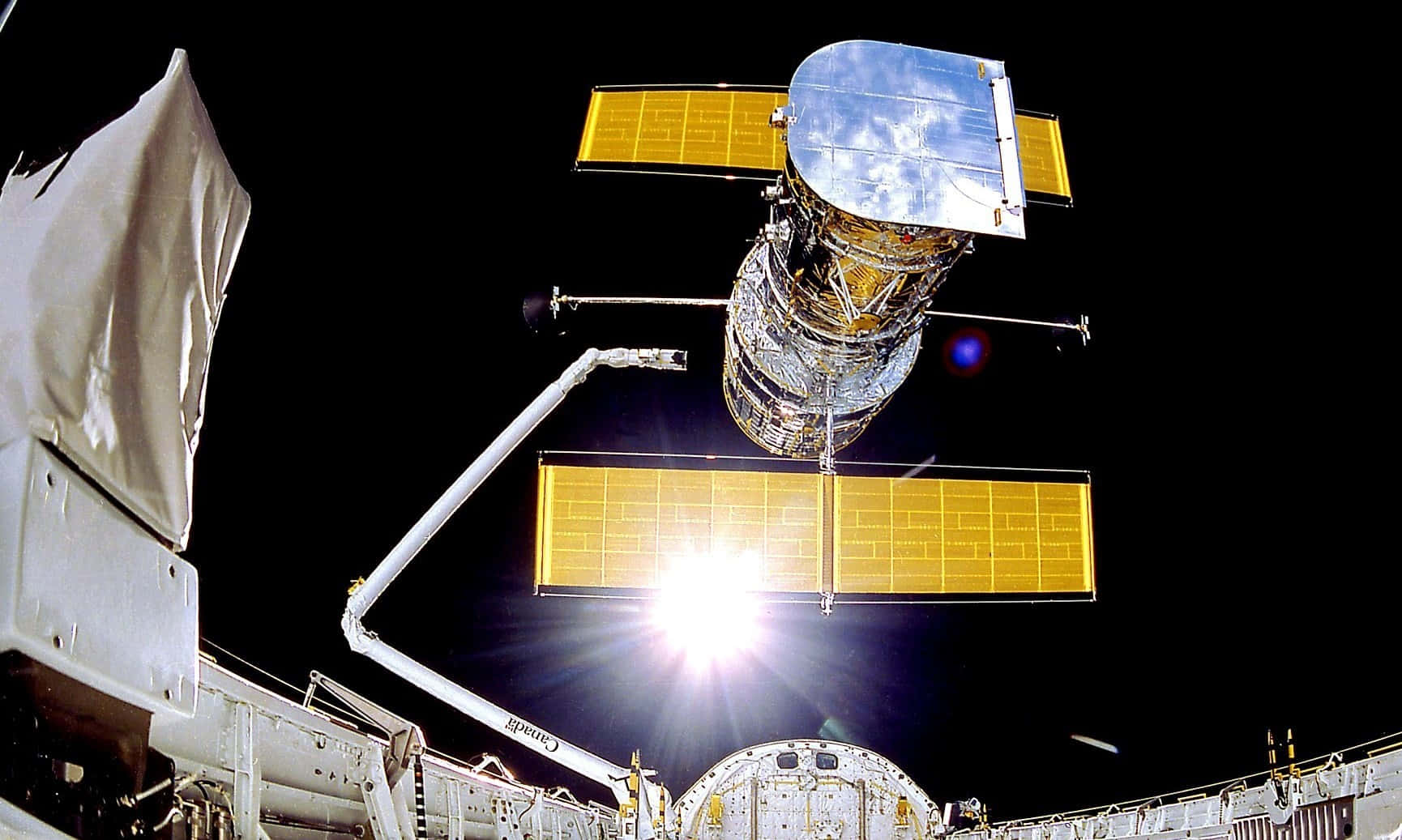 太空 桌布 壁紙 — 一顆帶有金色太陽能板及反射性機身的衛星，在黑色虛空中漂浮，伴隨明亮的太陽耀斑。