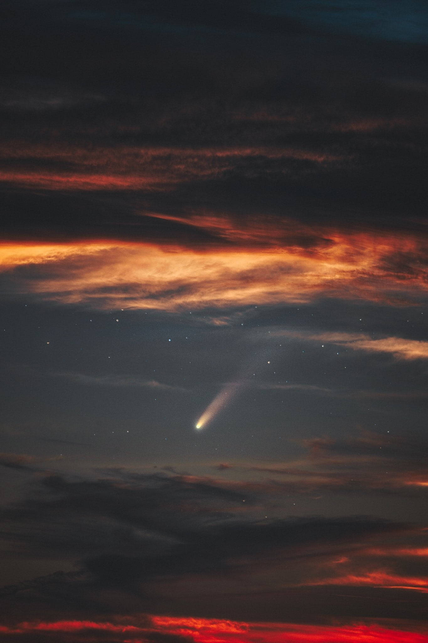 夜空 桌布 壁紙 — 一顆彗星劃過暮色天空，天空被火橙色和深緋紅色的雲彩點綴，上方是繁星點點。