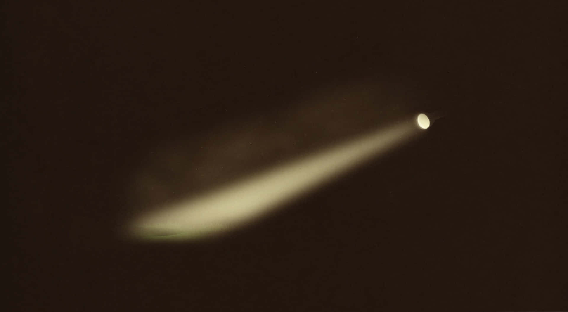Flashlight 桌布 壁紙 — 一顆彗星在深棕色宇宙背景下發出柔和黃色尾巴的光芒。
