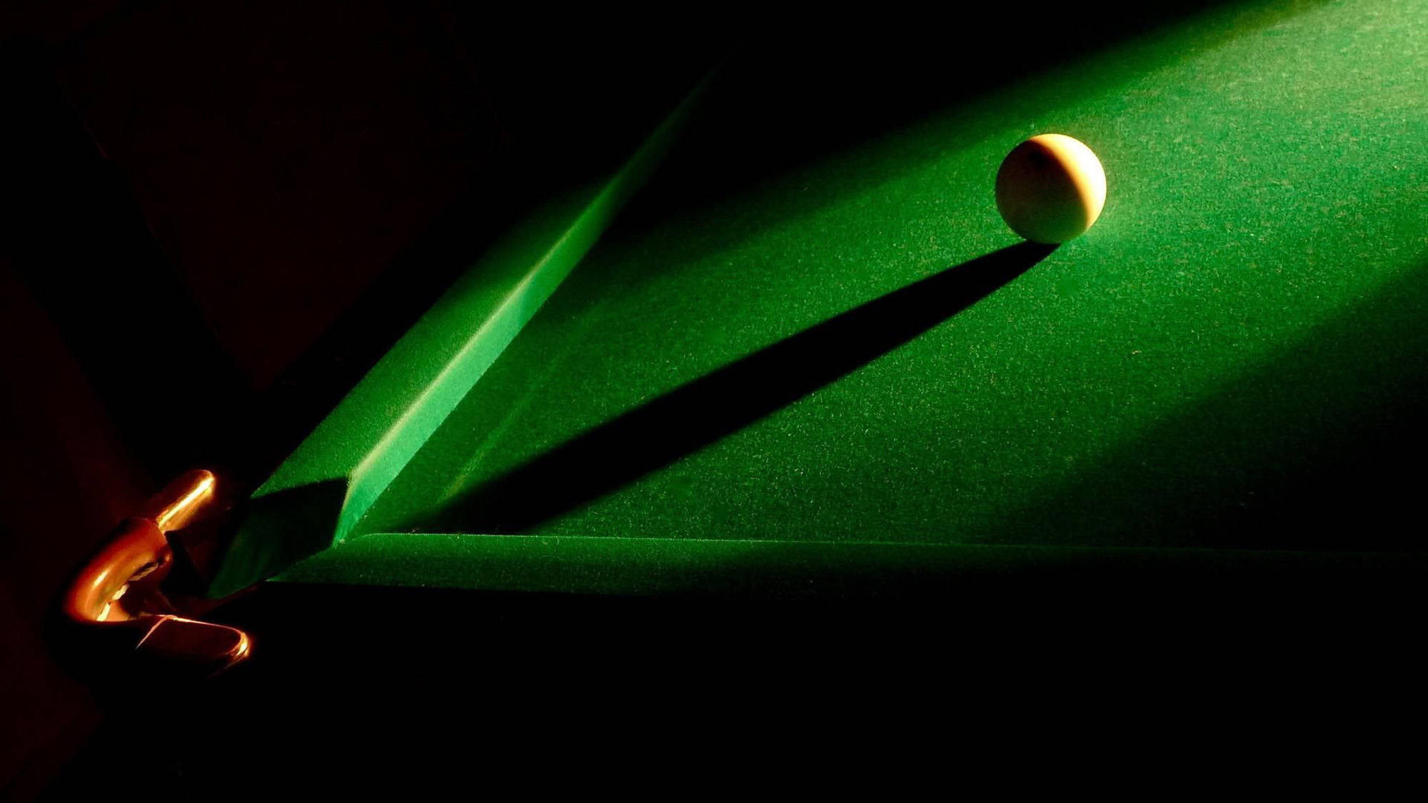 Snooker 桌布 壁紙 — 一顆撞球在近乎黑暗的環境中，於綠色絨布桌上戲劇性地被聚光燈照射著。