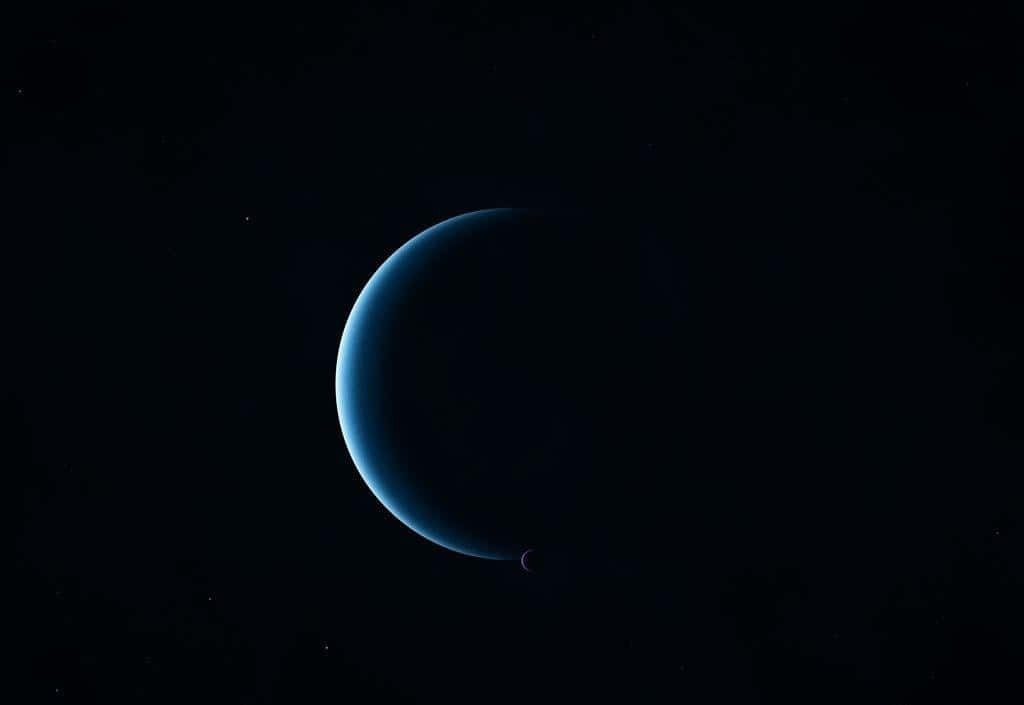 Neptune 桌布 壁紙 — 一顆新月形藍色行星在佈滿星星的黑色虛空中柔和發光，附近有一顆小衛星在軌道上運行。