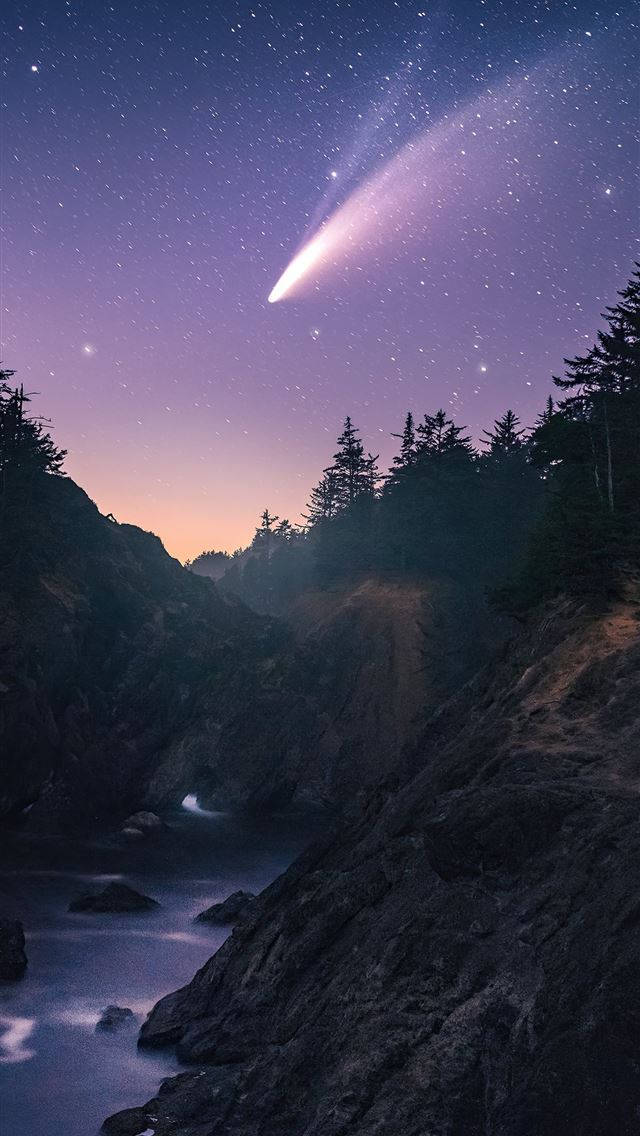 山景 桌布 壁紙 — 一顆明亮的彗星劃過佈滿星星的黃昏天空，下方是崎嶇的海岸峽谷，有流動的水。