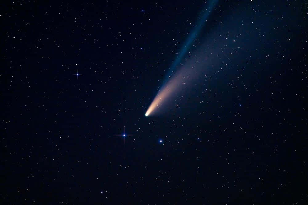 太空 桌布 壁紙 — 一顆明亮的彗星劃過滿天星斗的夜空，留下一條發光的藍色和橙色尾巴。