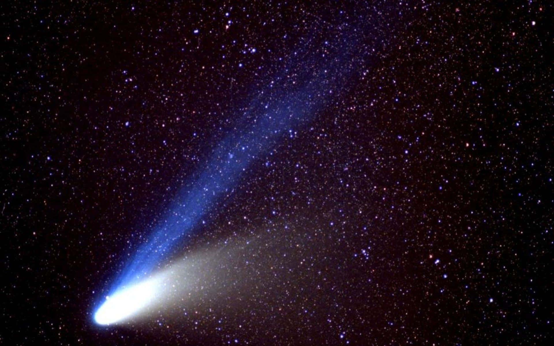comet 桌布 壁紙 — 一顆明亮的彗星劃過繁星點點的夜空，留下一條發光的藍色尾巴。