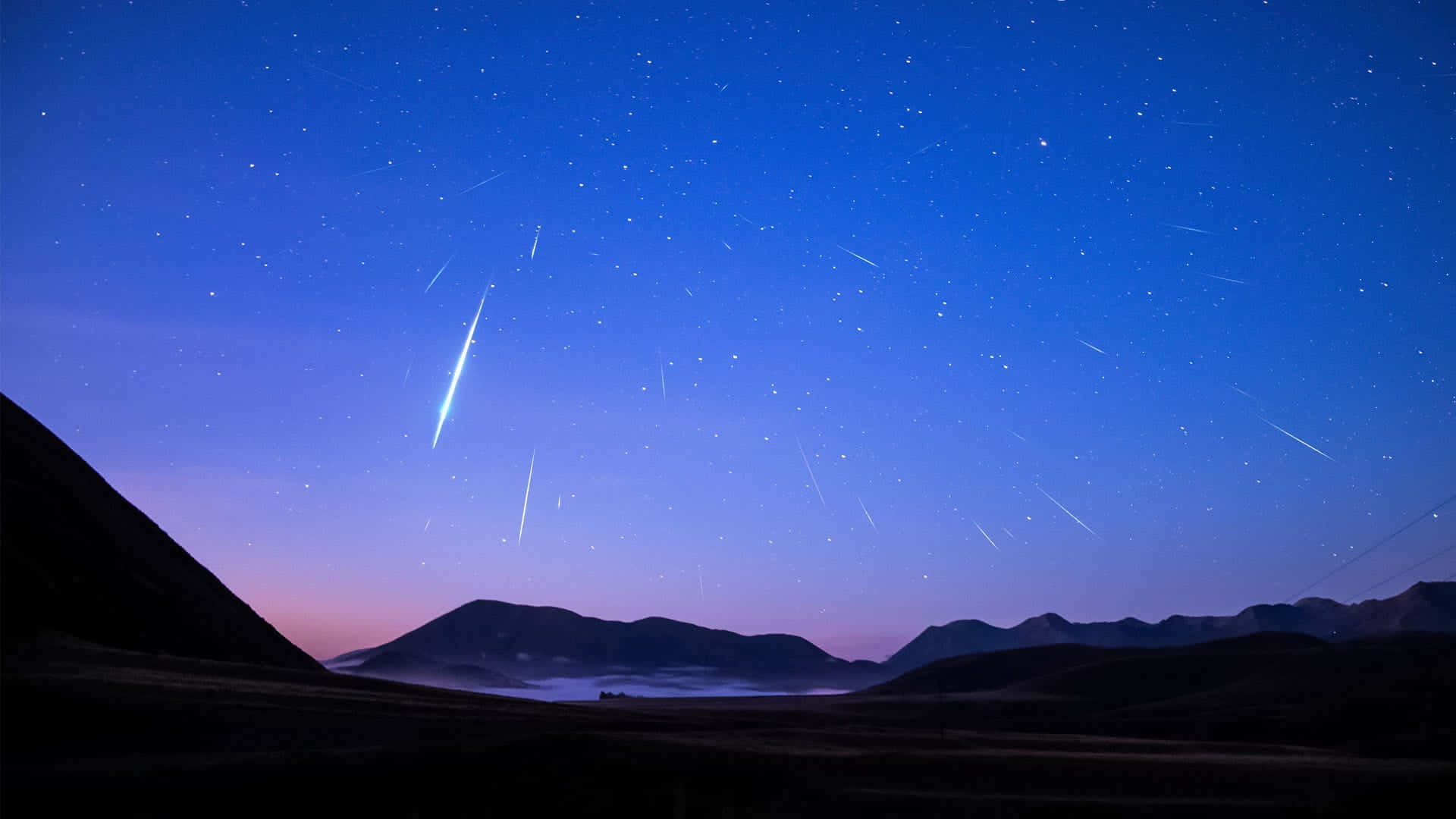 meteor 桌布 壁紙 — 一顆明亮的流星劃過佈滿星空的暮色天空，下方是輪廓分明的山脈和霧氣瀰漫的山谷。