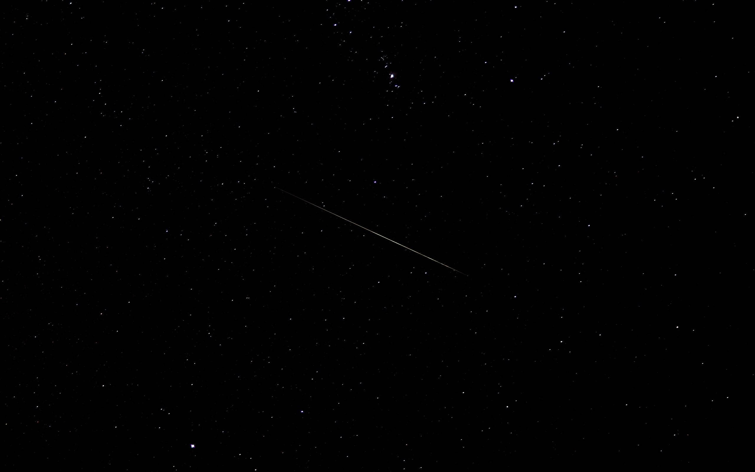 macOS 桌布 壁紙 — 一顆明亮的流星斜斜地劃過佈滿星星的黑色夜空。
